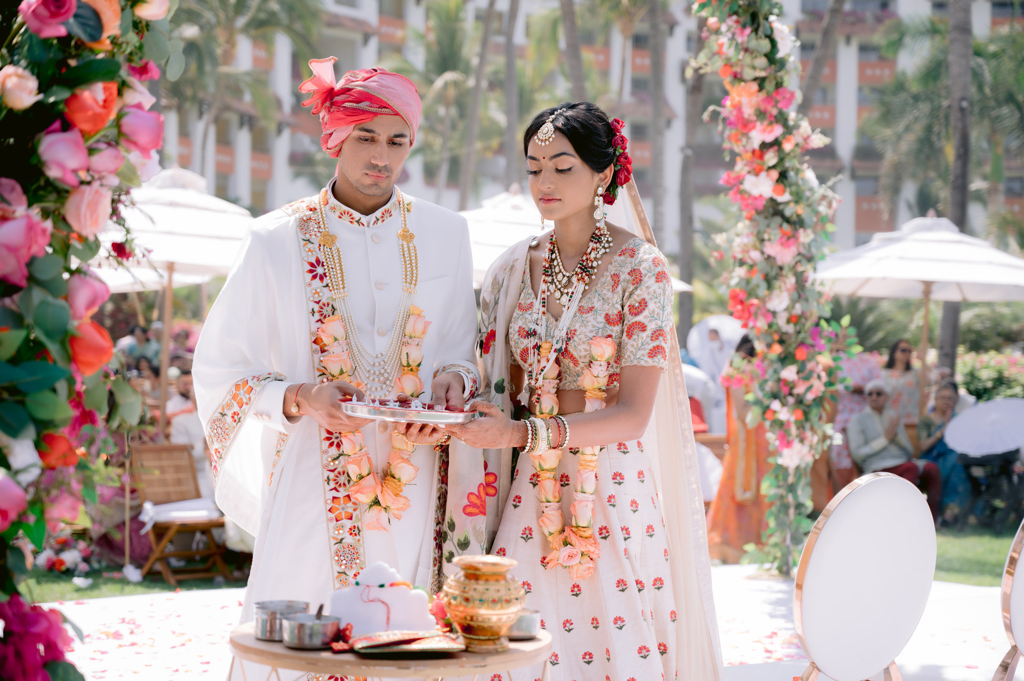 a couple in traditional indian attire standing under a floral arch