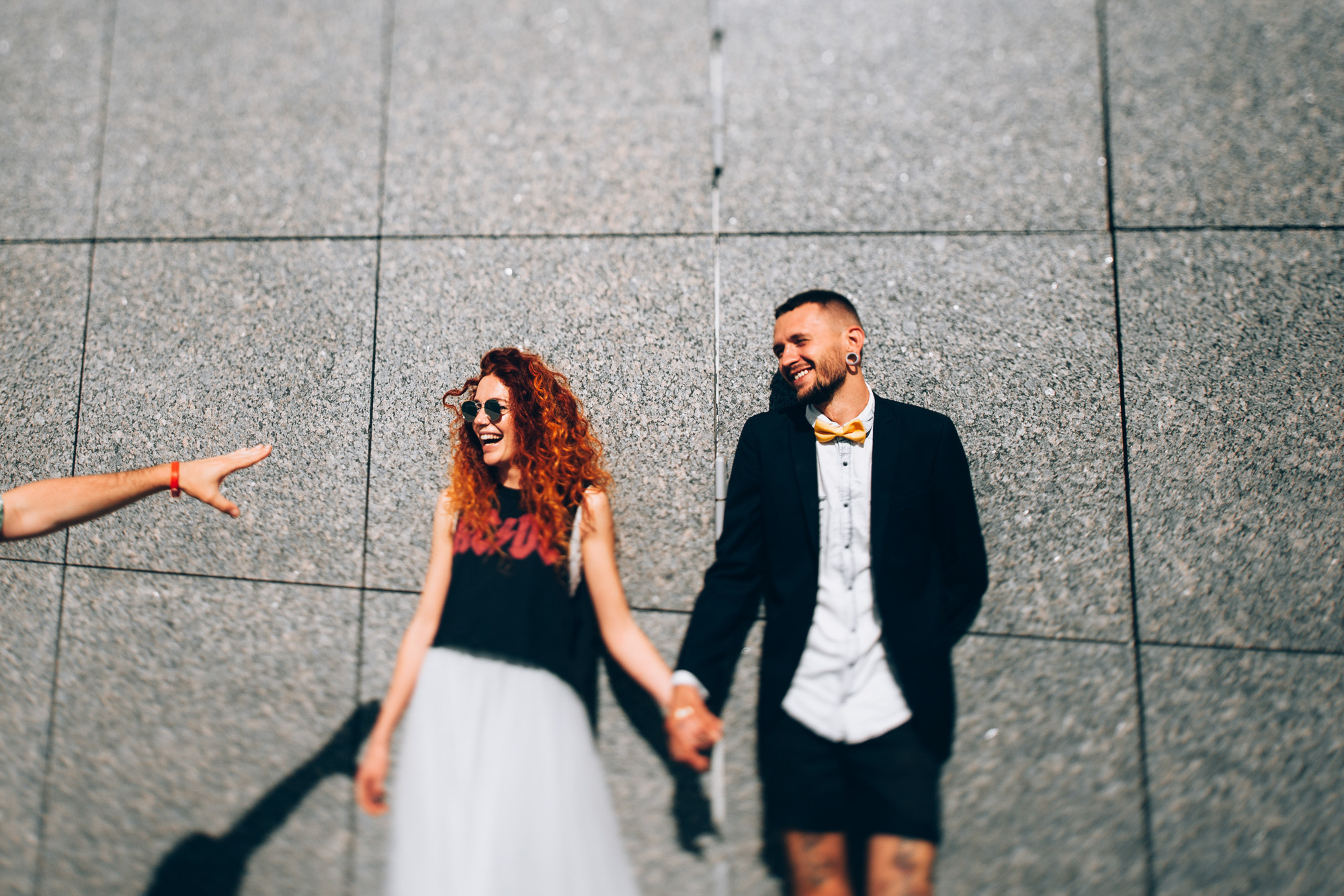 a couple holding hands and walking down a sidewalk