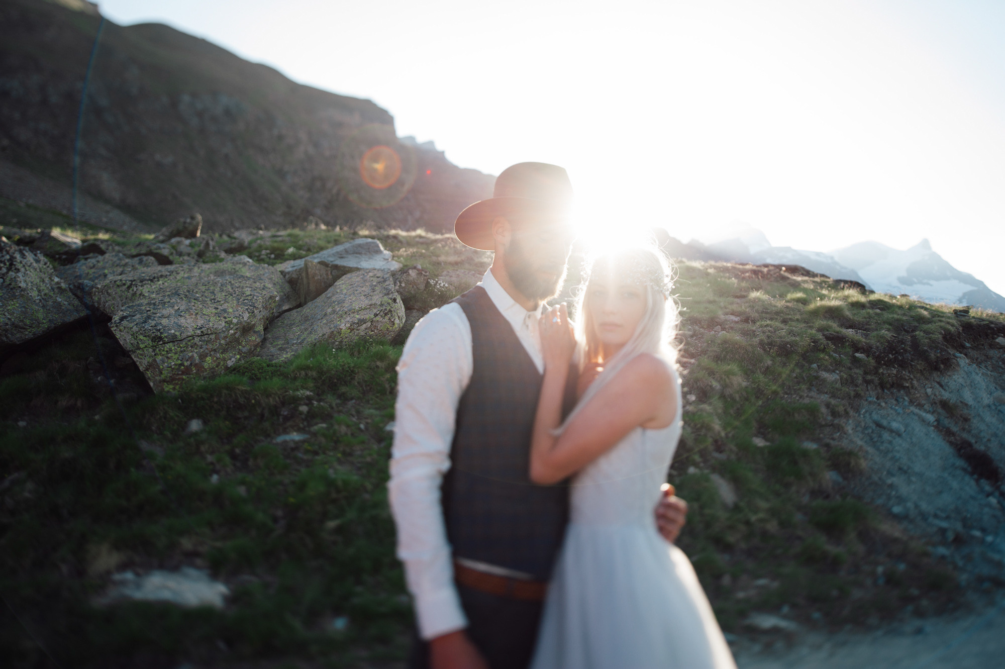 a bride and groom standing on a rocky mountain