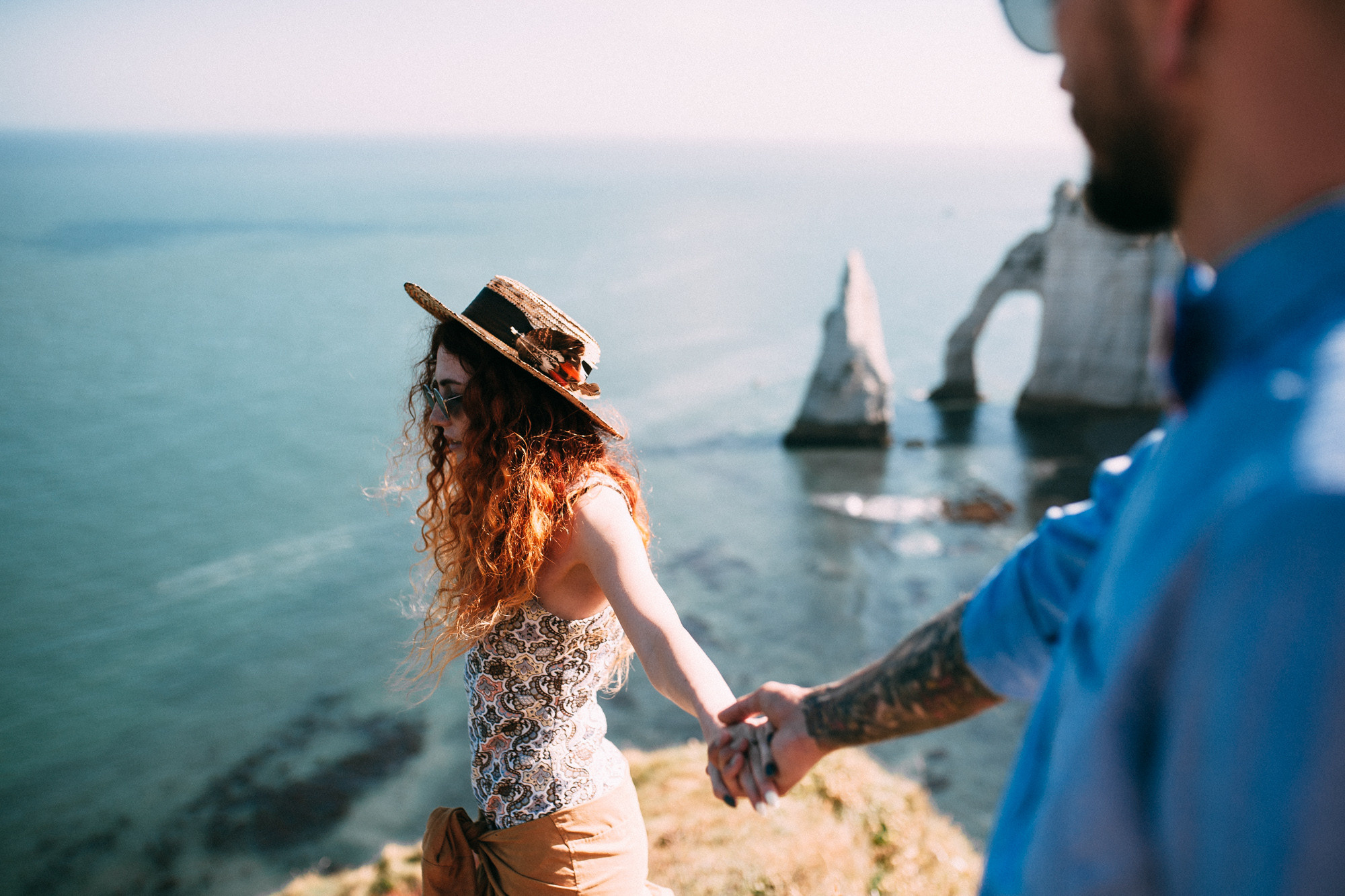 a man and woman holding hands on a cliff