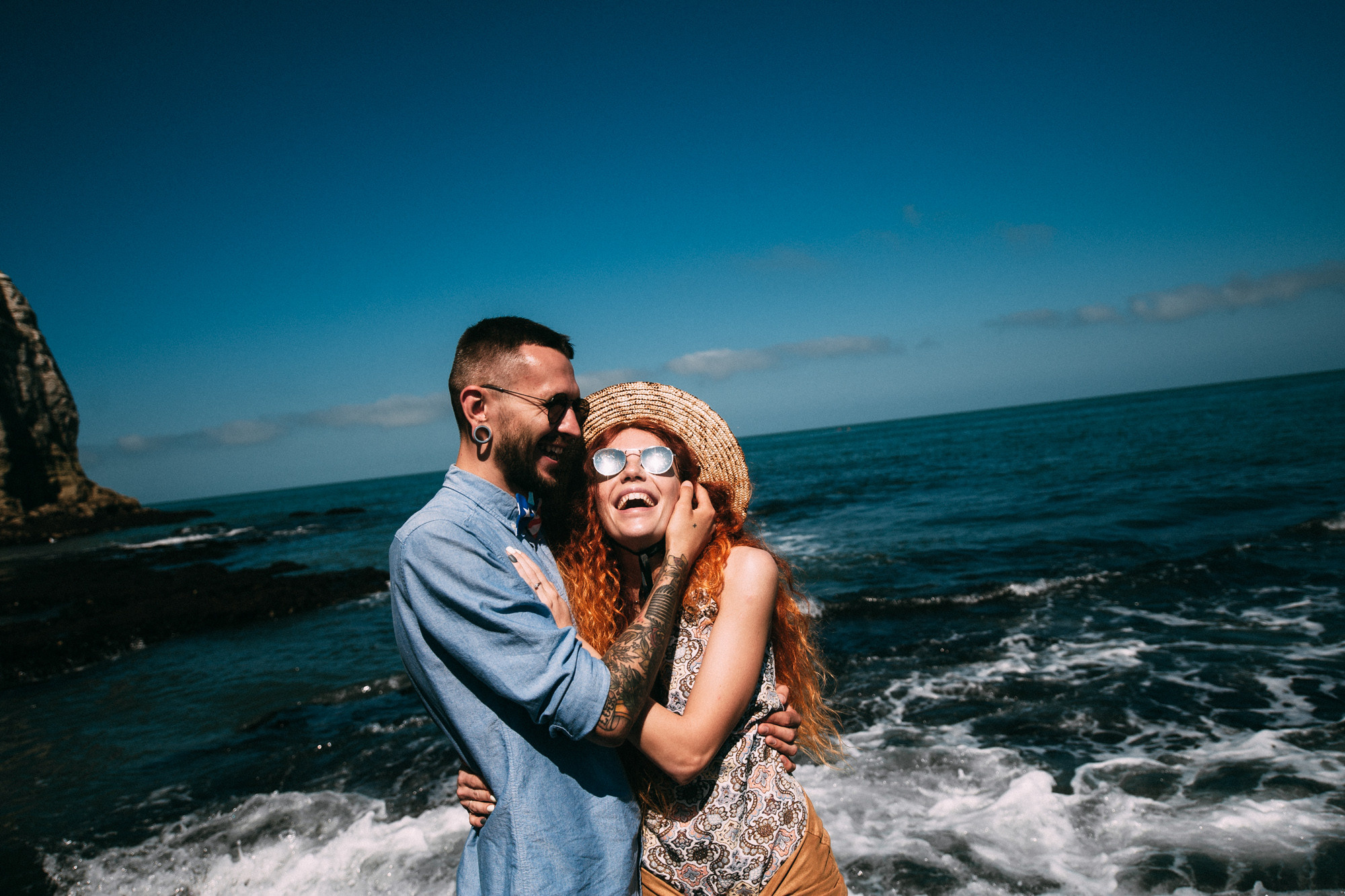a couple standing on a beach next to the ocean