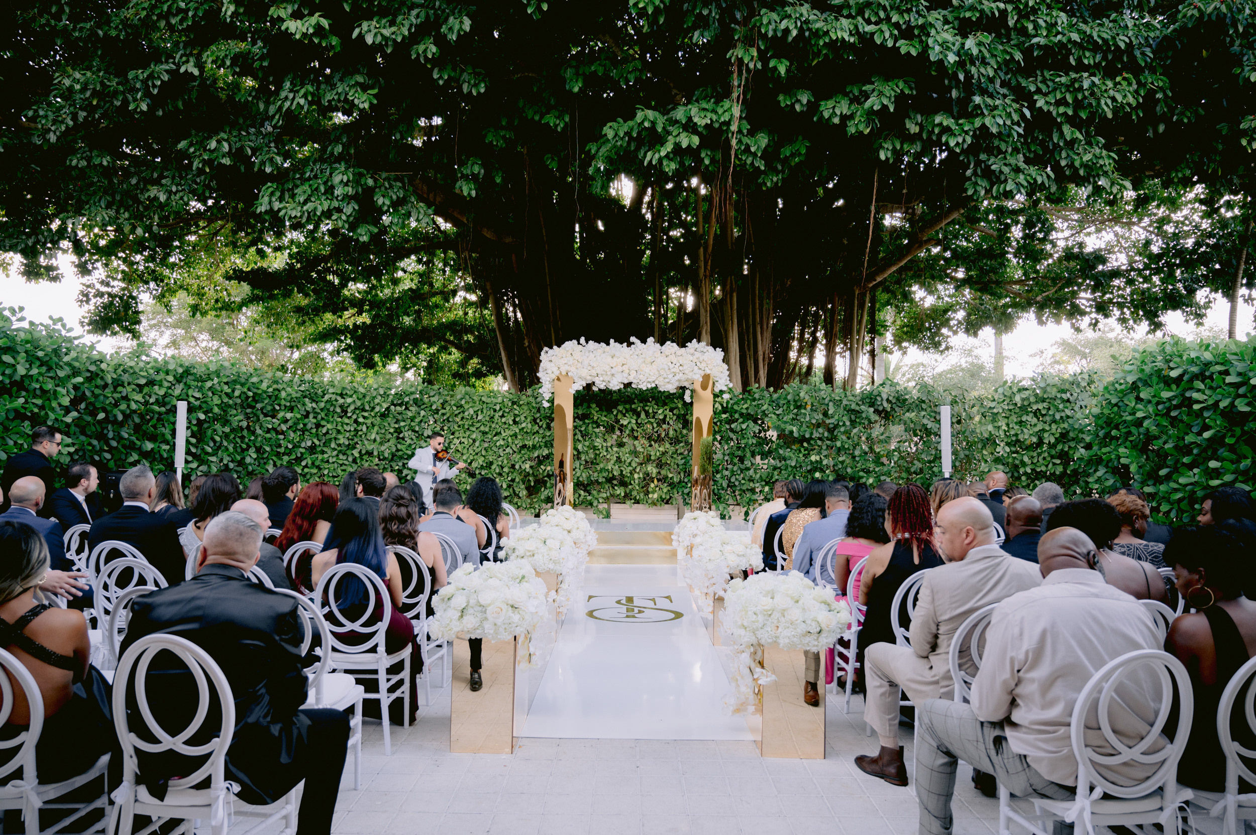 a wedding ceremony with white flowers and white chairs