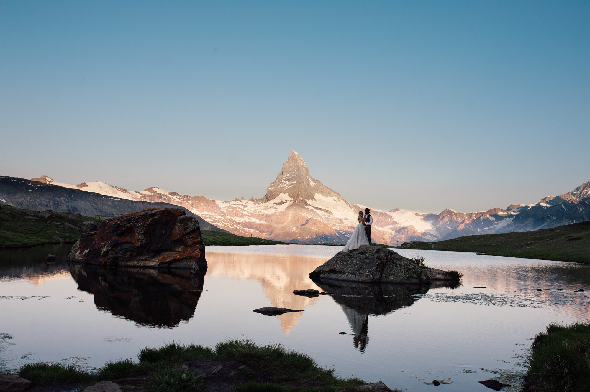 a bride standing on a rock in a lake
