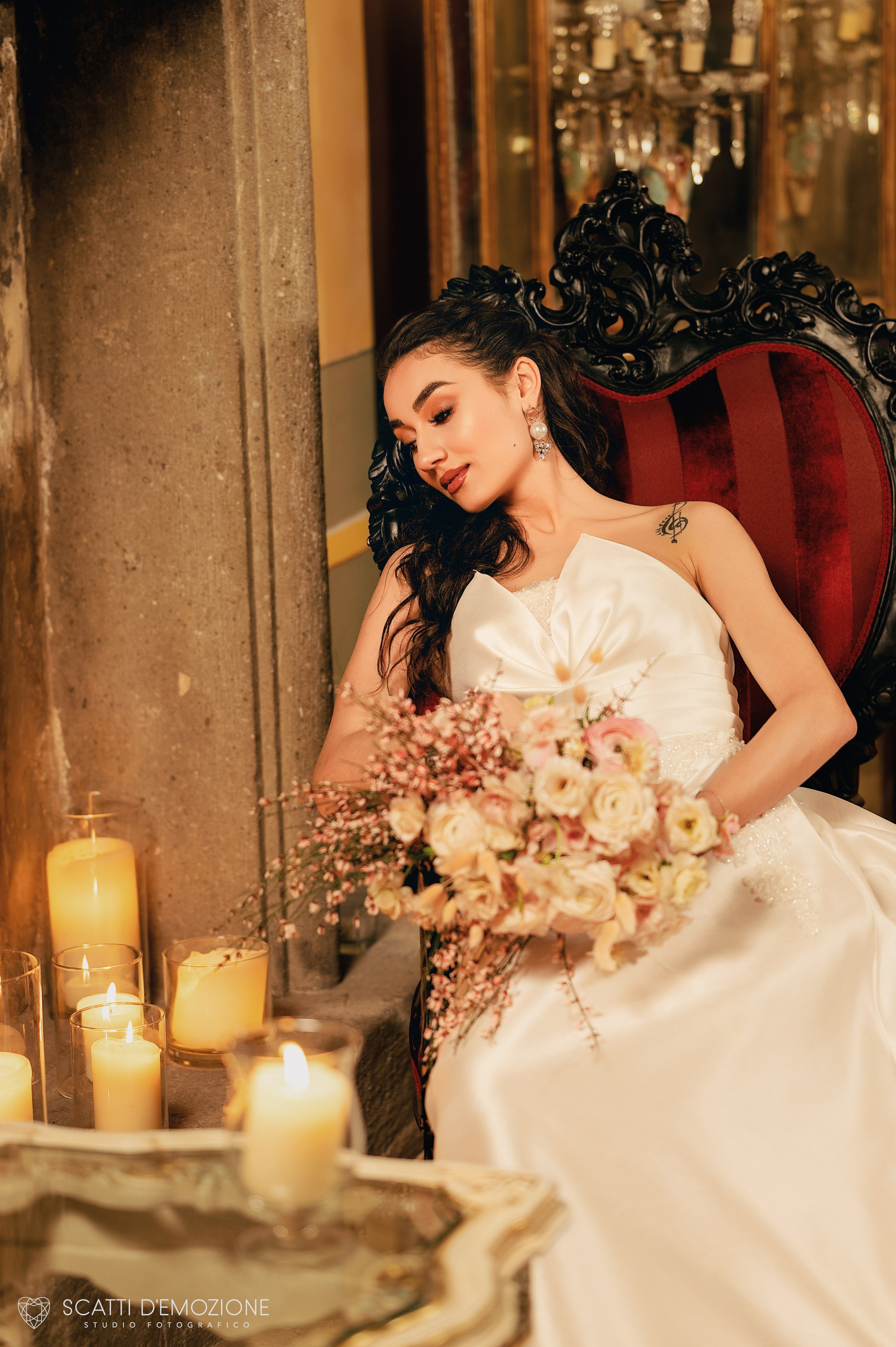sposa seduta su una poltrona di lusso in un ambiente romantico con candele