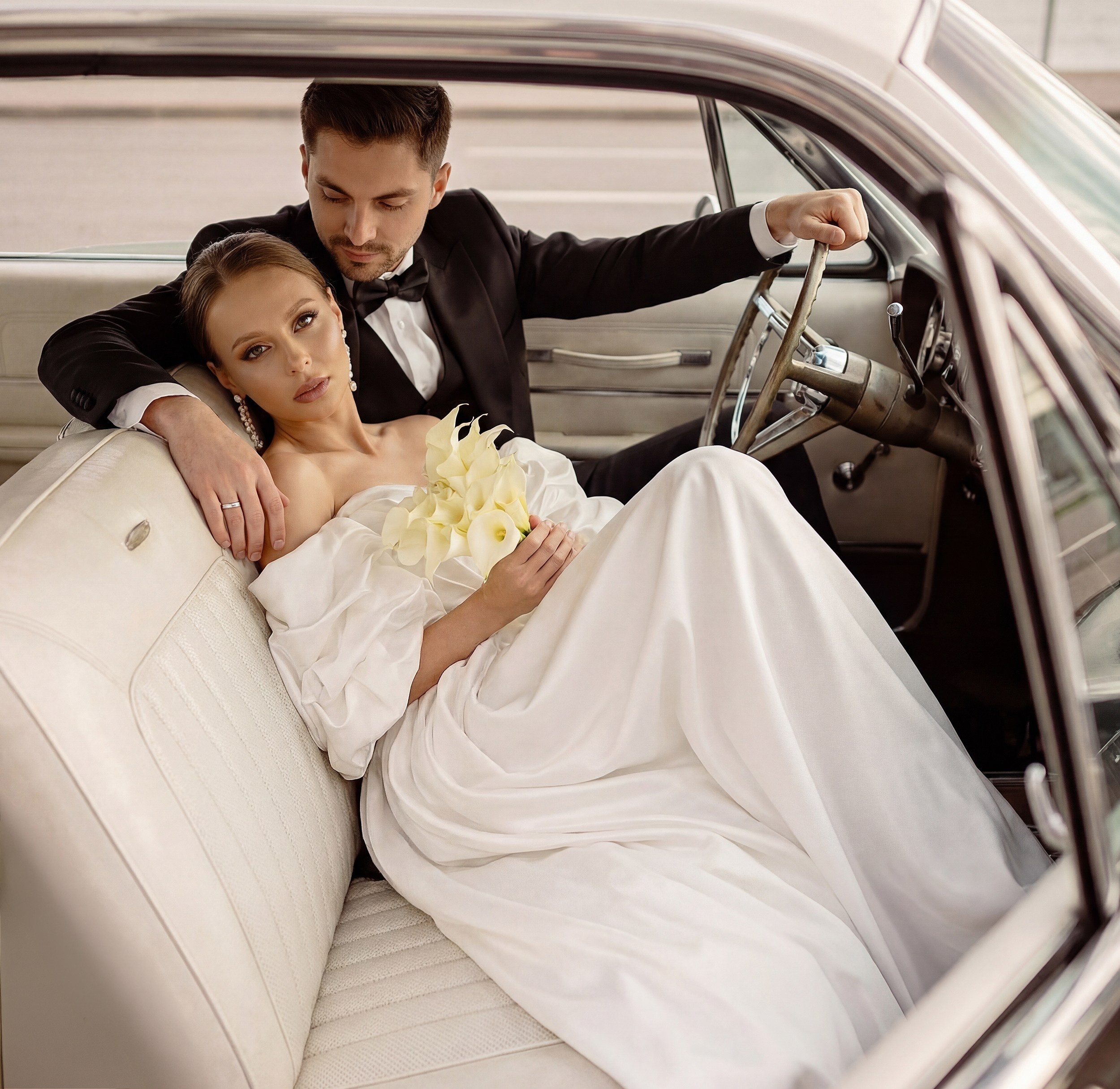 Bride and groom posing together inside a classic vintage car. Romantic wedding photography in Killarney.