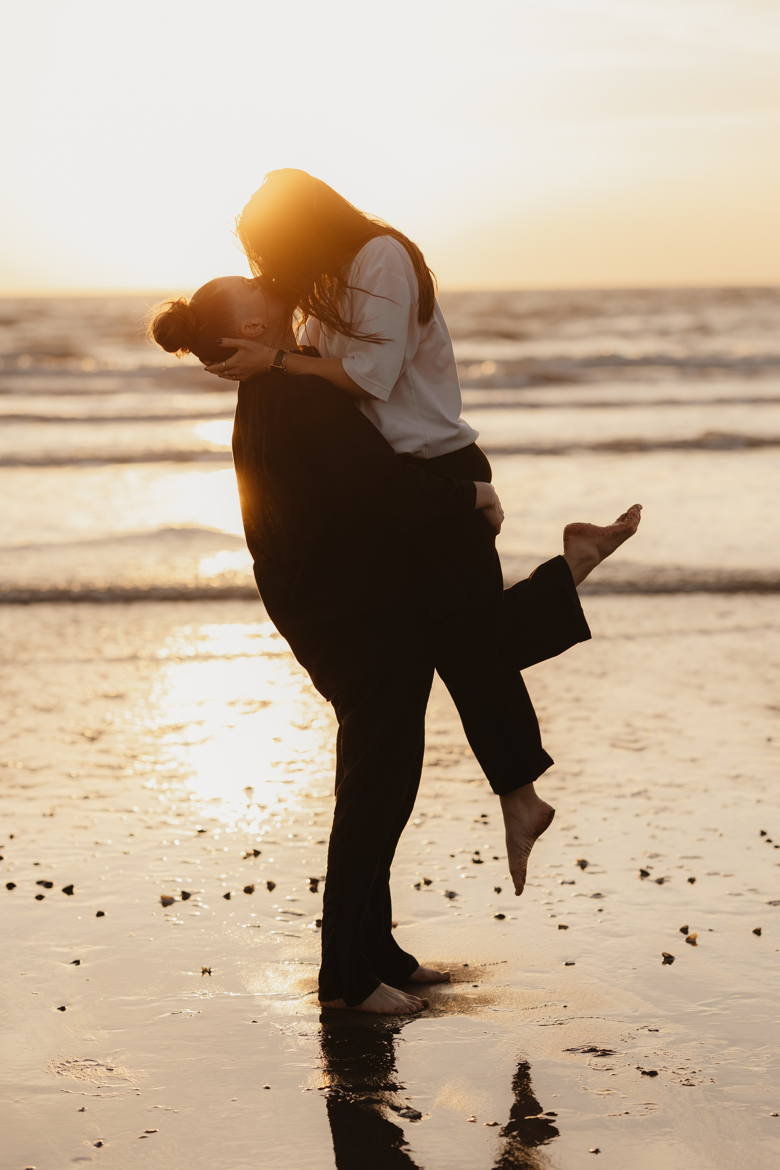 Couple de femmes s’embrassant à la plage au coucher du soleil, séance photo lifestyle