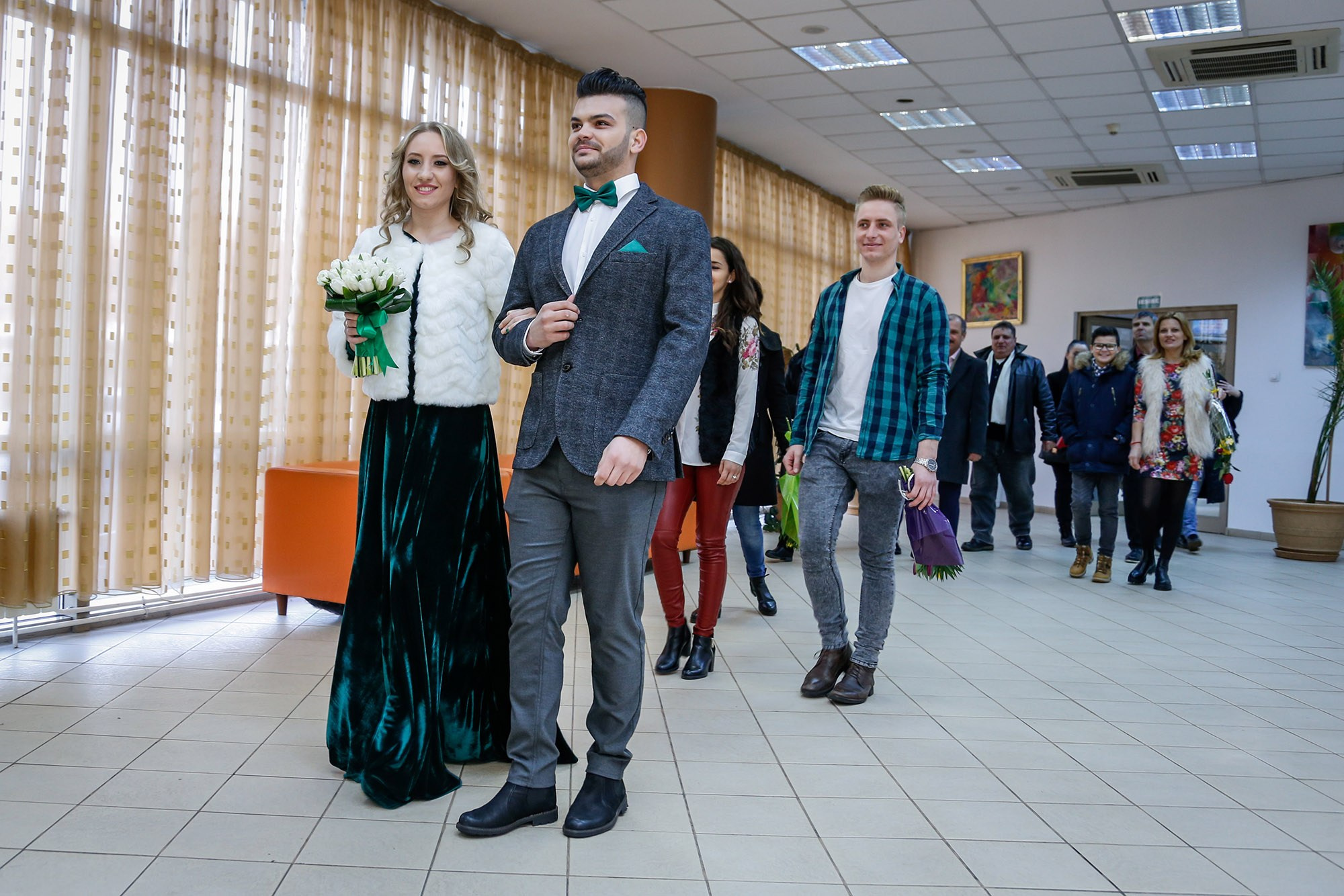 Bride and groom walking emotionally into the registry office ceremony room, surrounded by guests, captured by a wedding photographer.