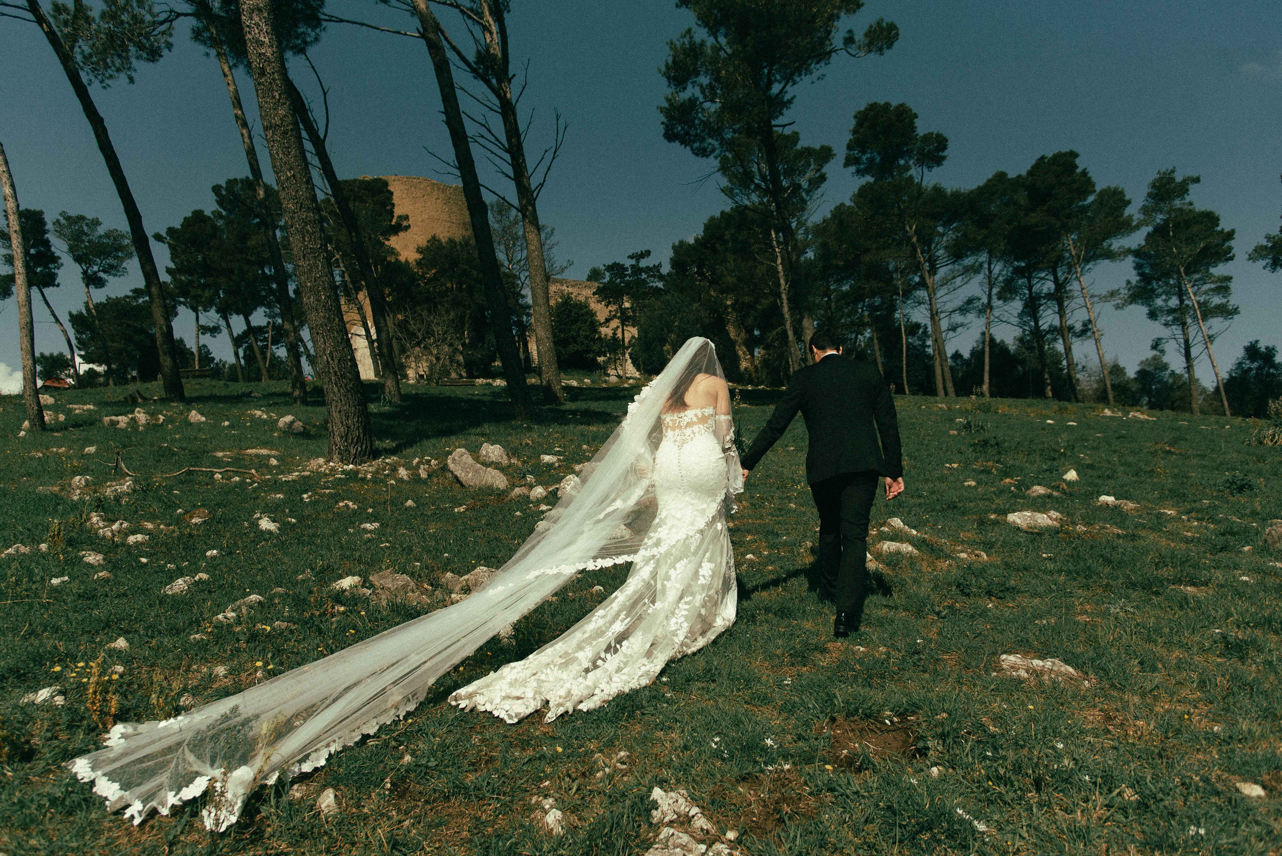 Bride and groom walking away in a garden, photographed from behind