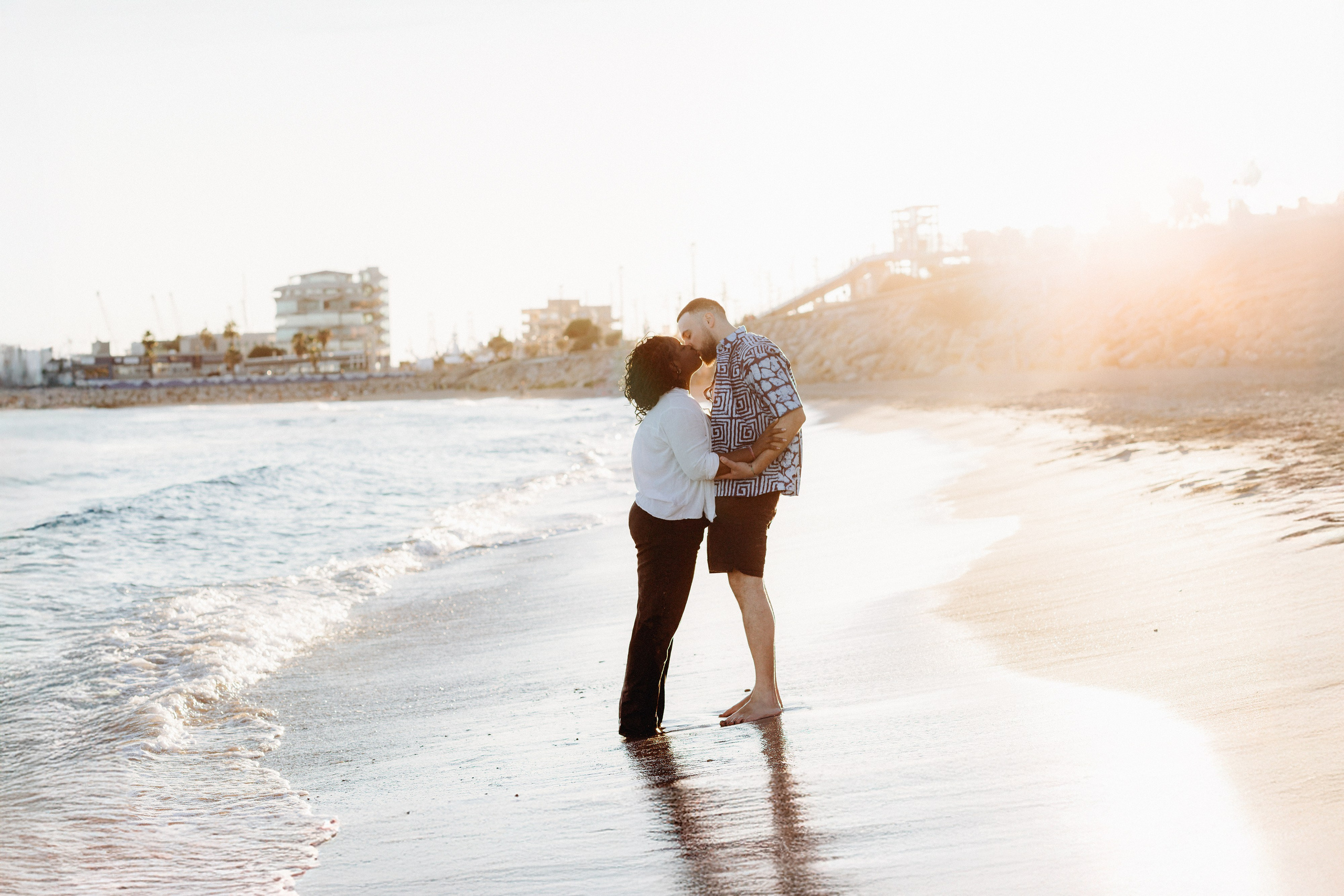 Beso al atardecer en la playa durante una sesión de historia de amor en Valencia, España — un tierno momento junto a la orilla, perfecto para quienes buscan sesiones románticas de pareja o de compromiso en Valencia y en toda España.