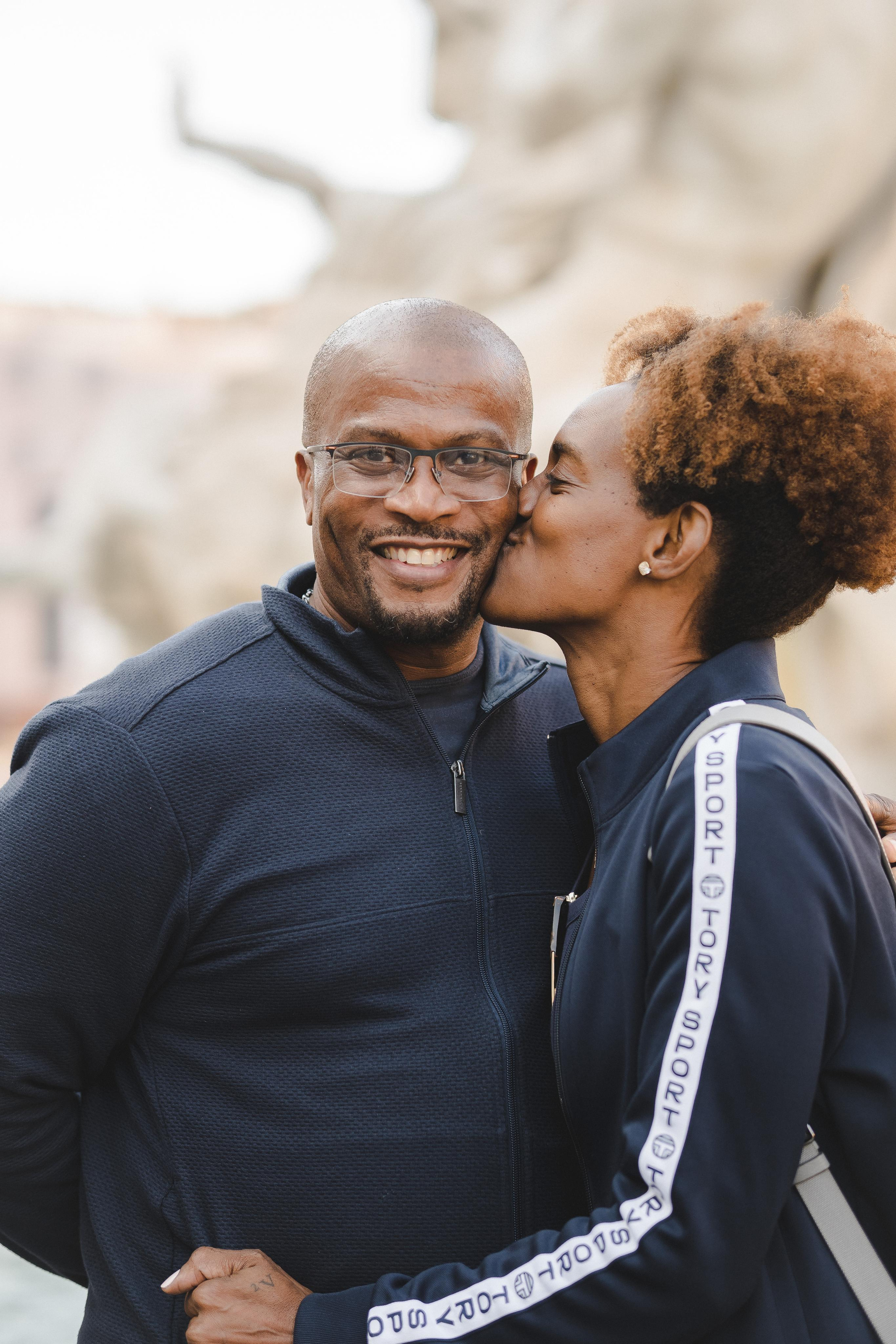 A woman kissing her husband on cheeks