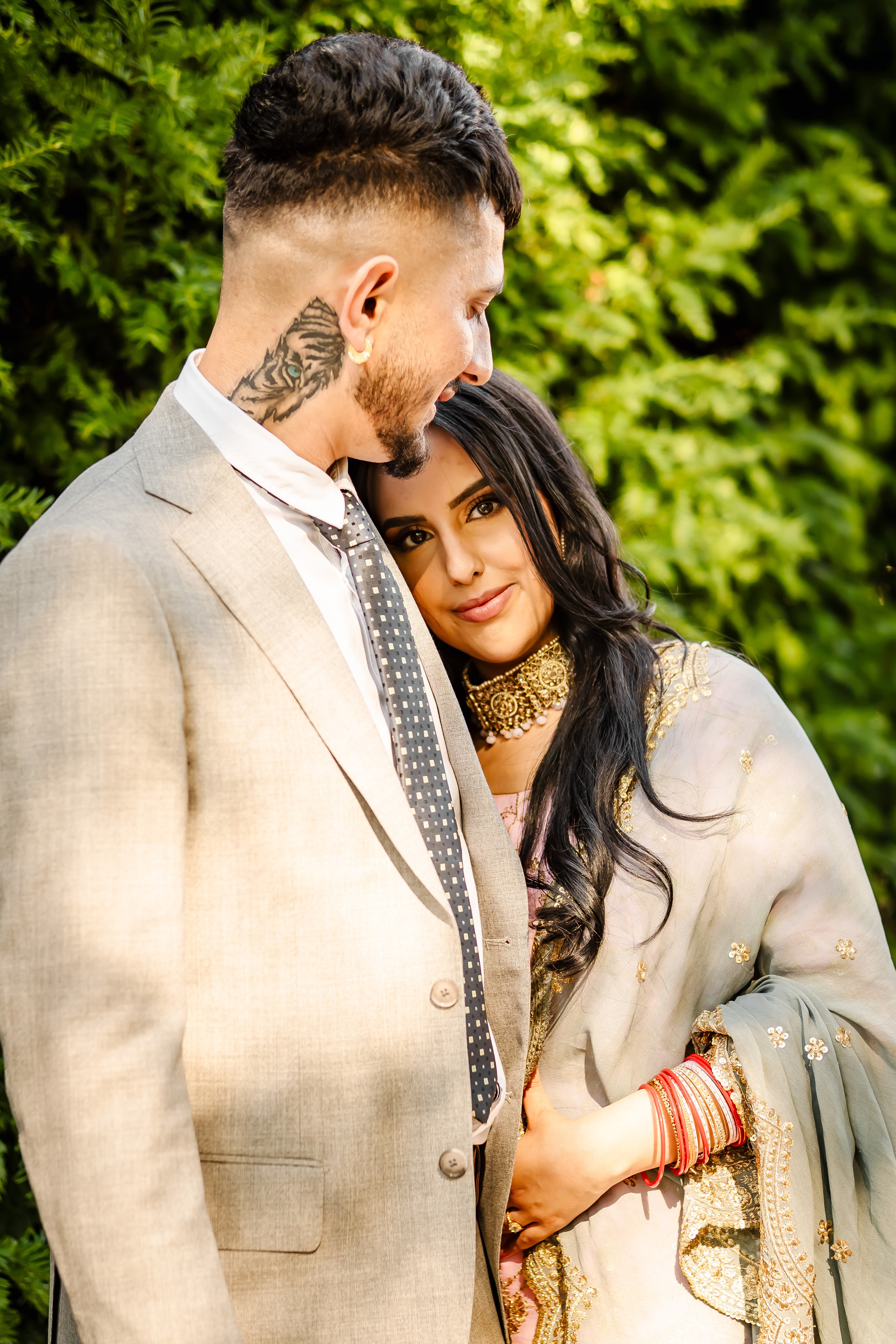 a woman wearing lehenga leaning on the chest of a man wearing a grey suit 