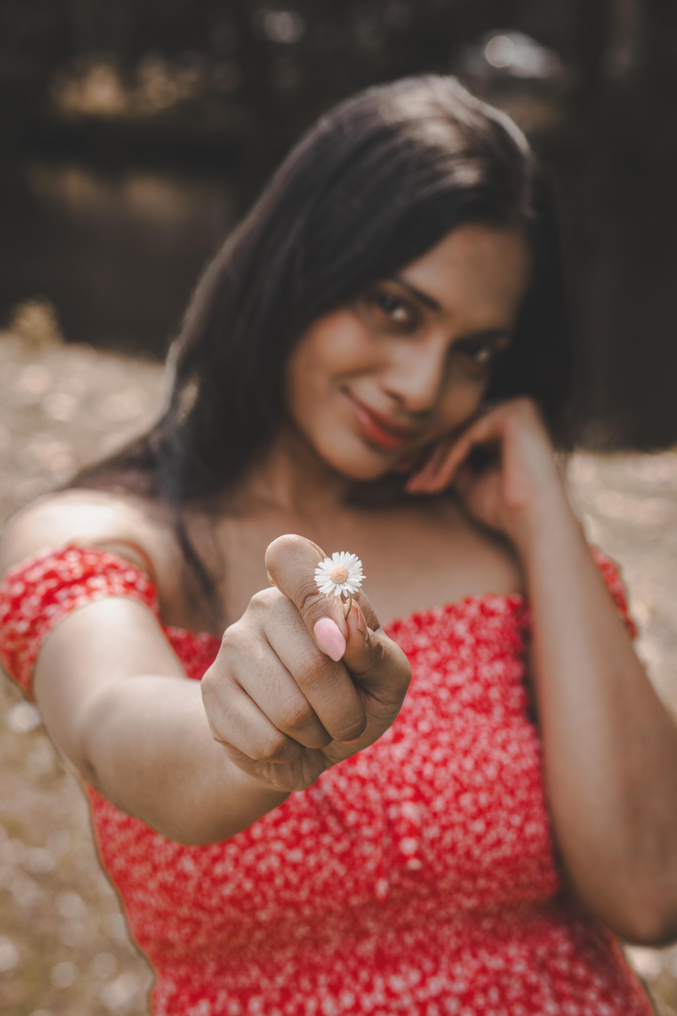 a woman holding a tiny white flower and wearing a red polka dress
