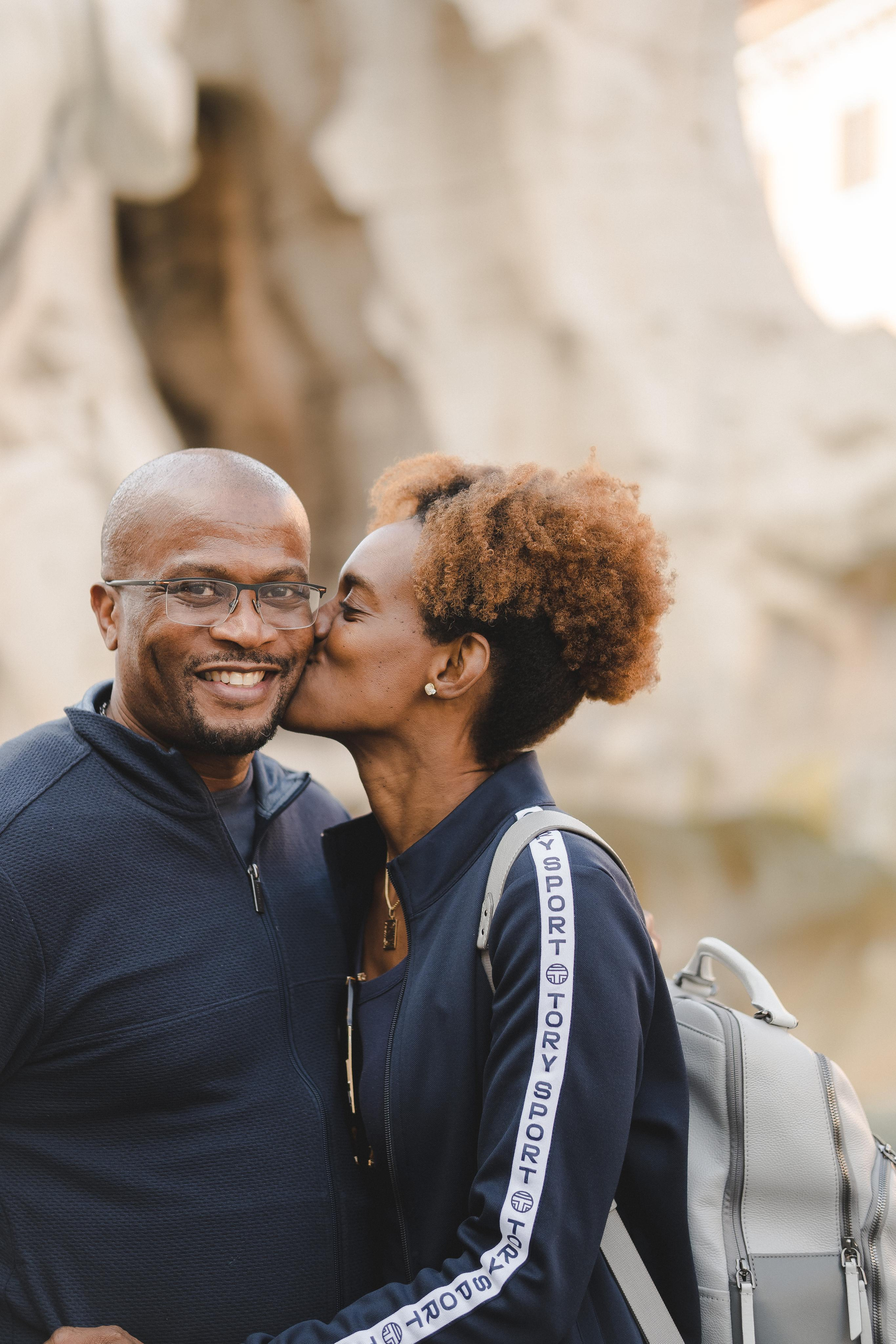 A woman kissing her husband on cheeks