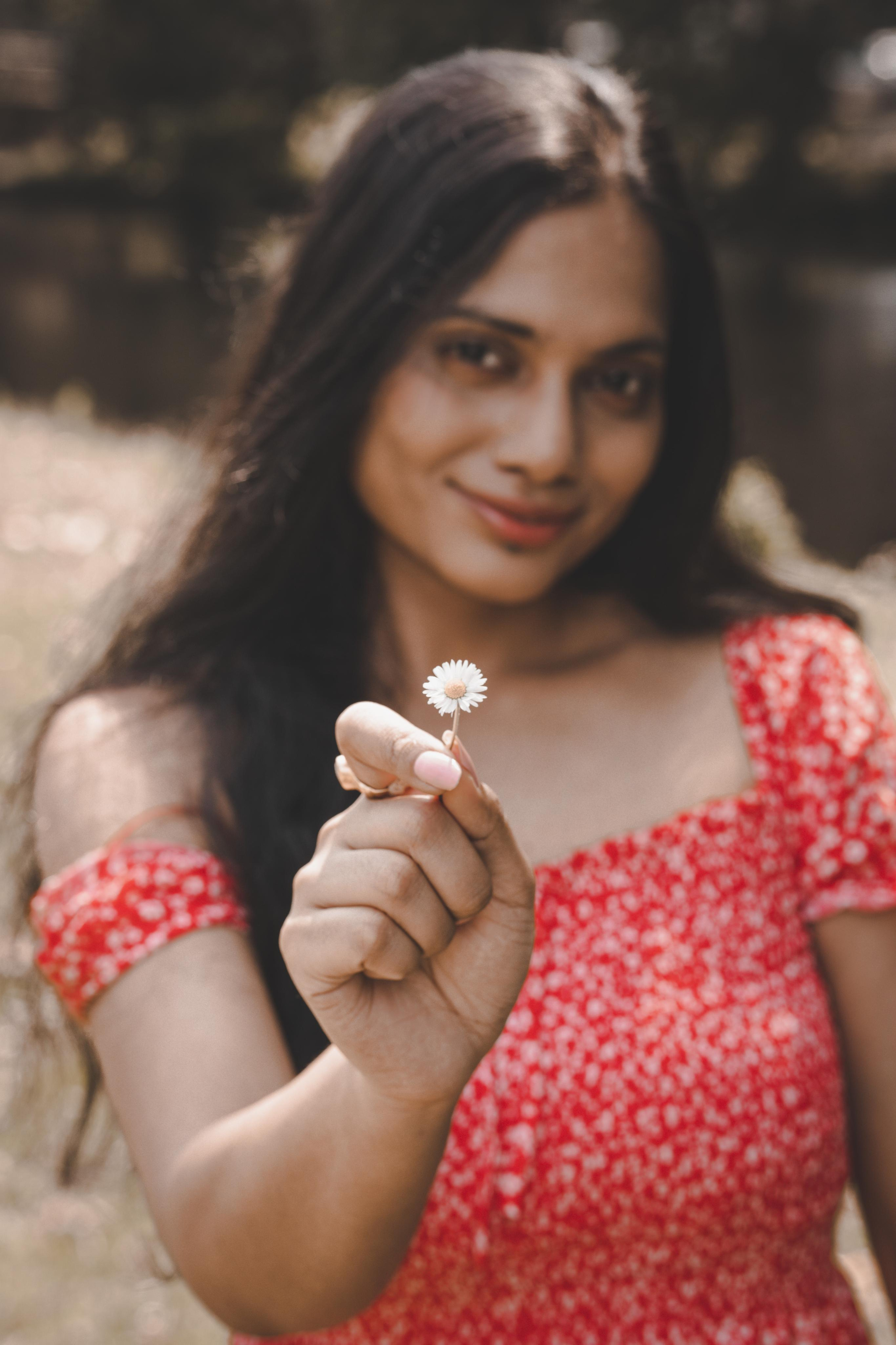 a woman holding a tiny white flower and wearing a red polka dress
