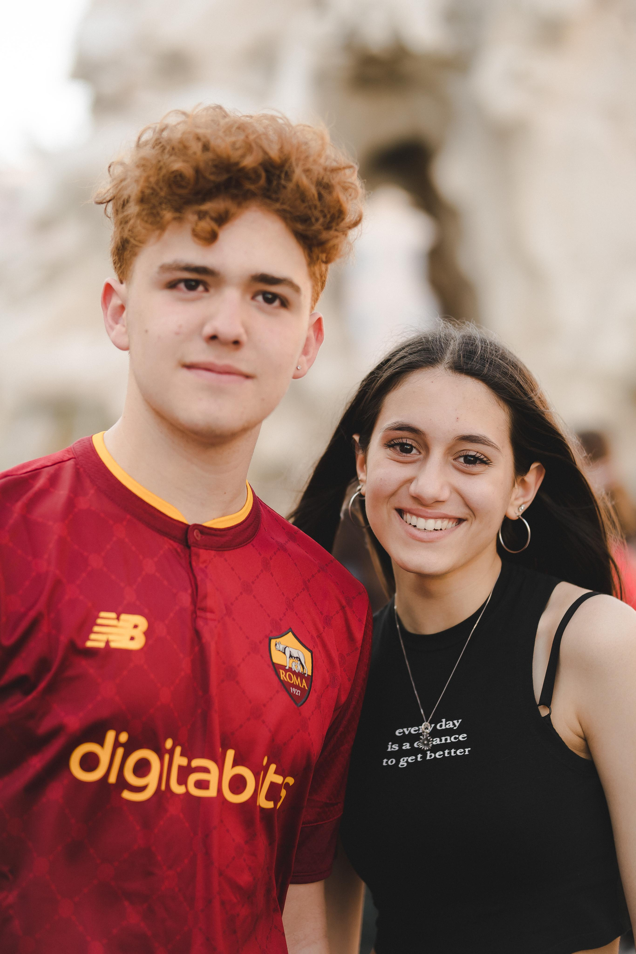 A boy wearing a red jersey and a girl wearing a black tank top and smiling
