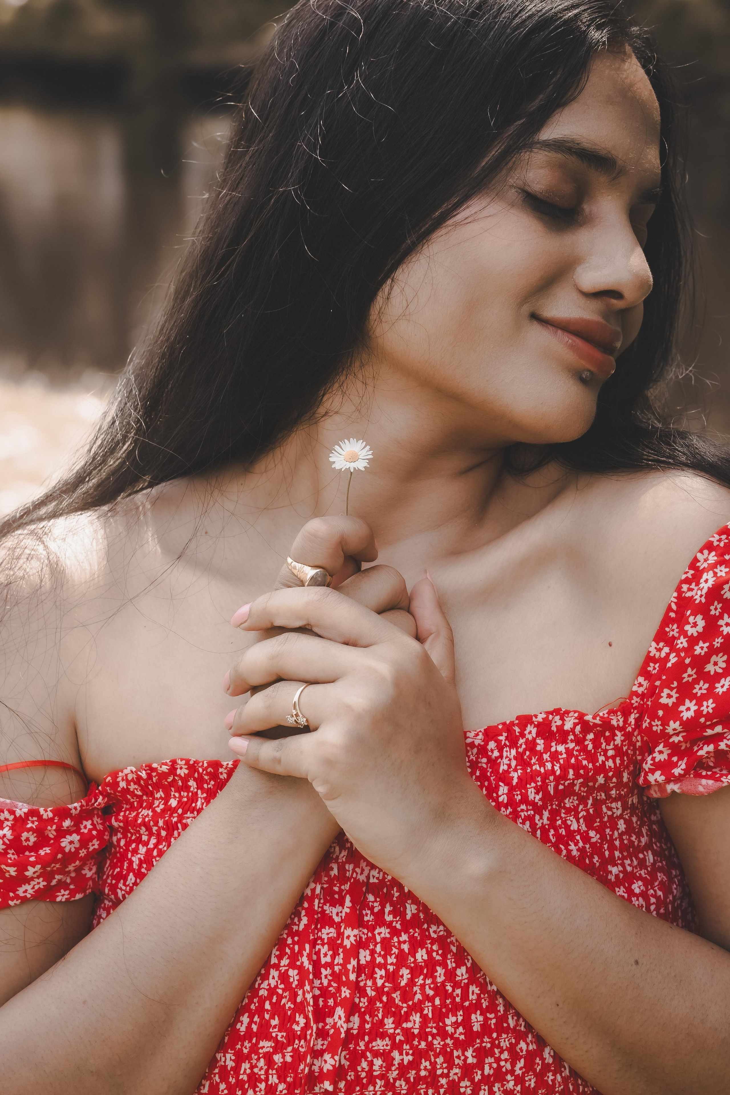 a woman holding a tiny white flower and wearing a red polka dress