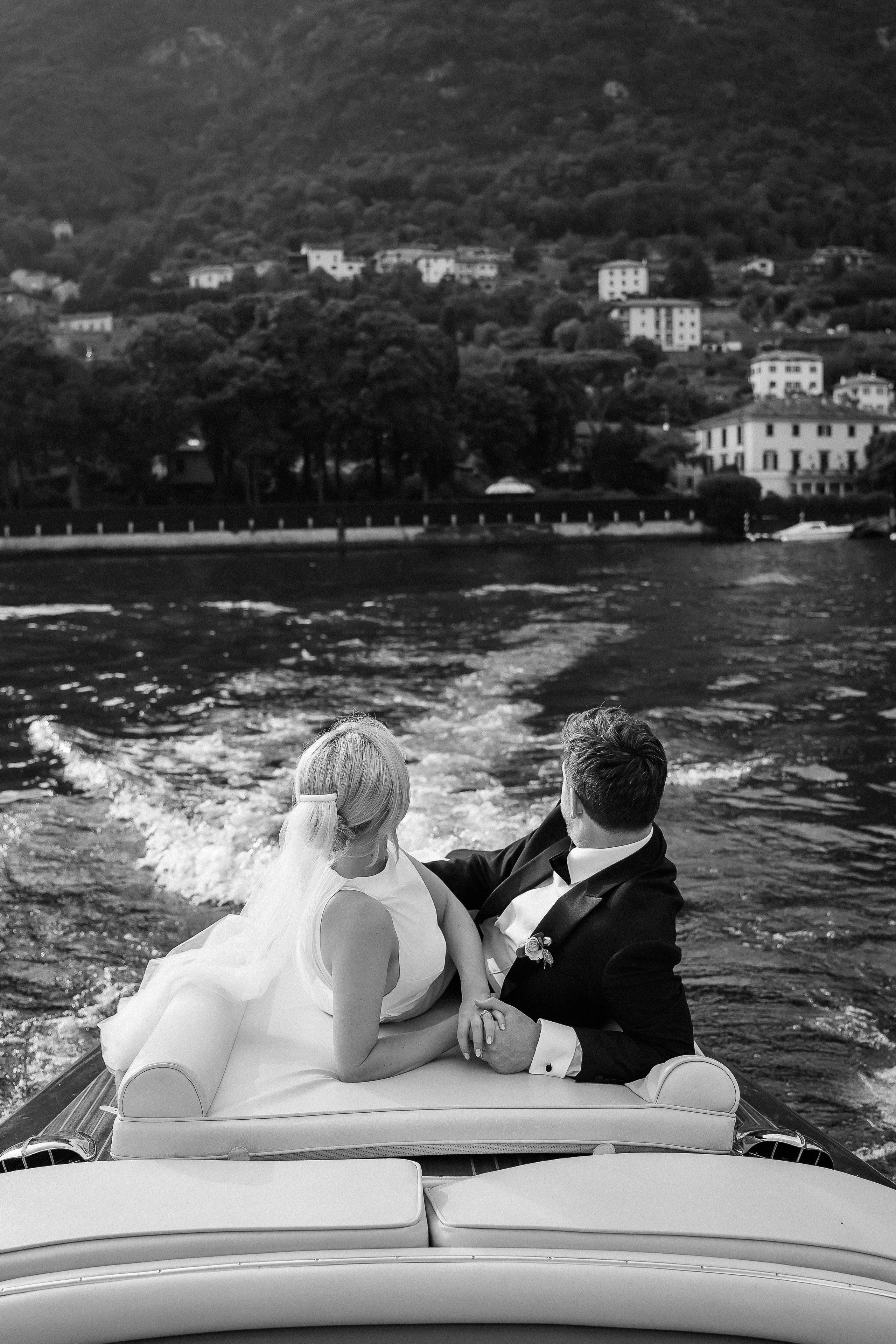 Black and white wide shot of the couple on the boat at Villa Lario, Lake Como, Italy