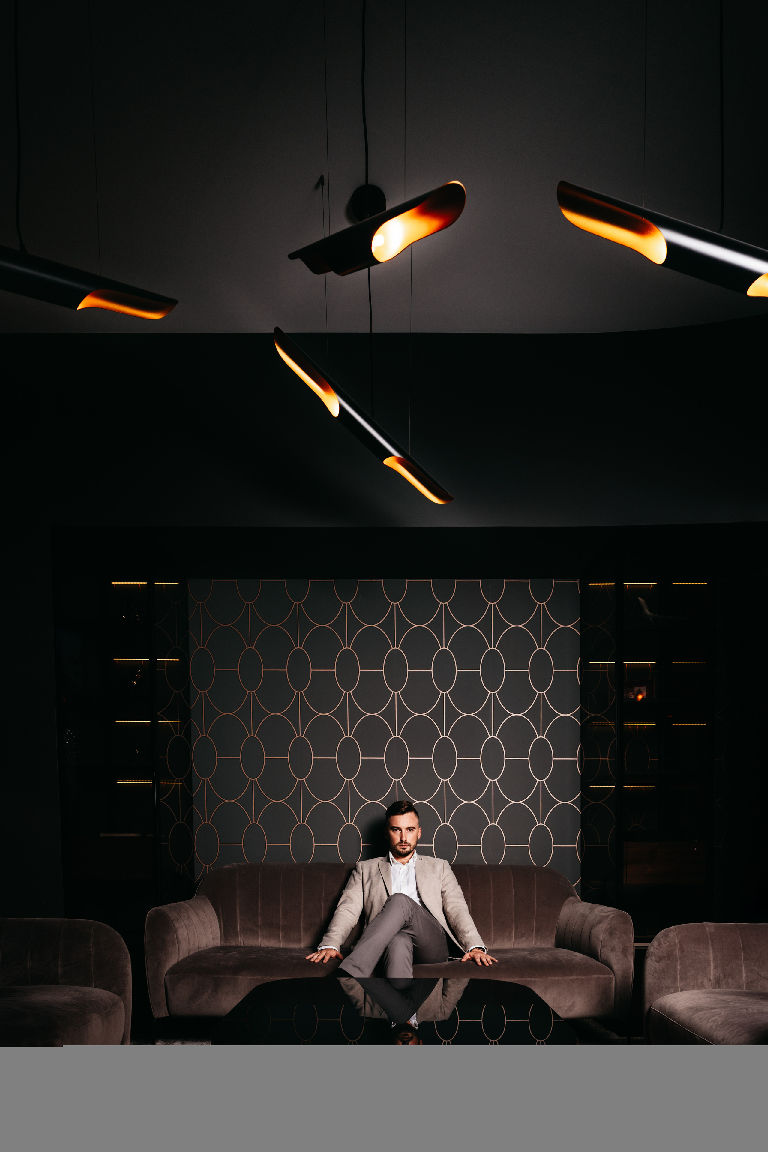 A person sitting alone in a modern lounge with soft lighting and minimalist decor, evoking solitude and introspection.