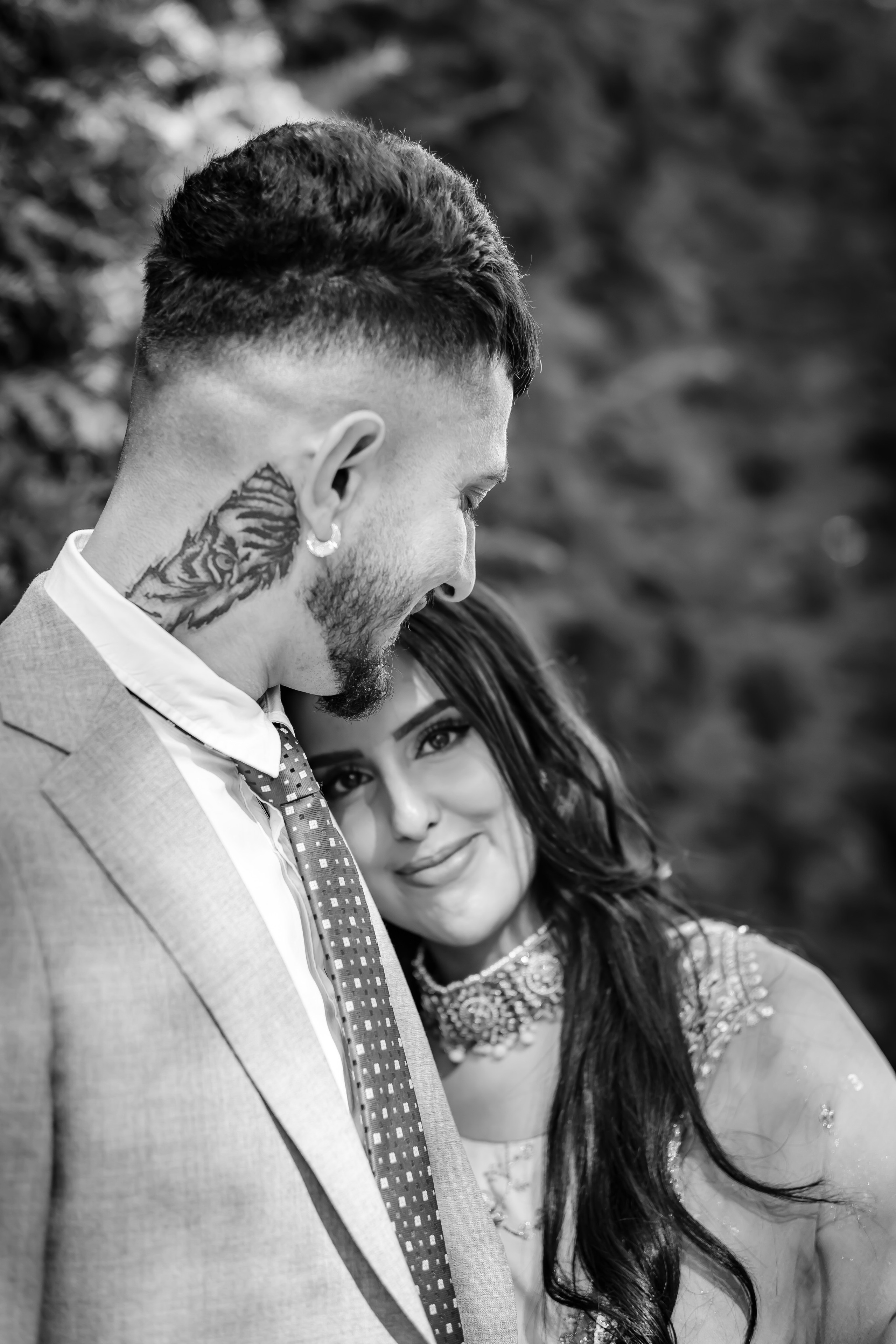 a woman wearing lehenga leaning on the chest of a man wearing a grey suit 