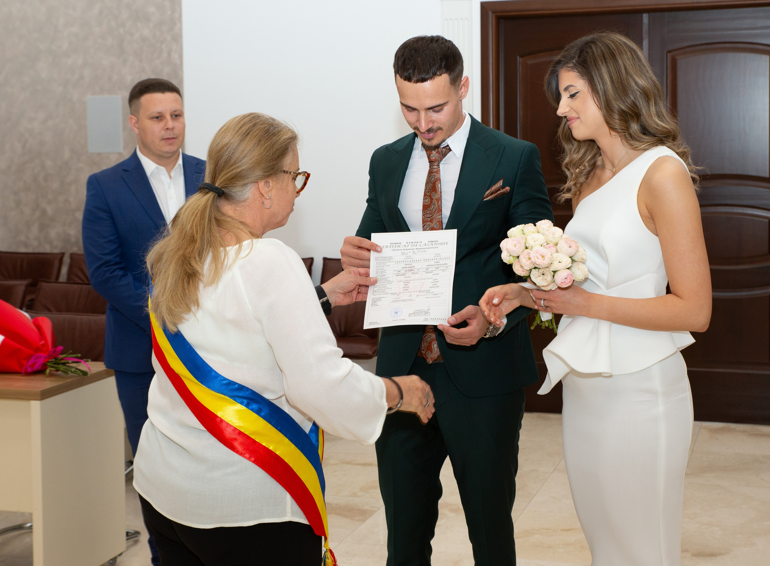 Couple receiving marriage certificate from official during civil wedding ceremony indoors.