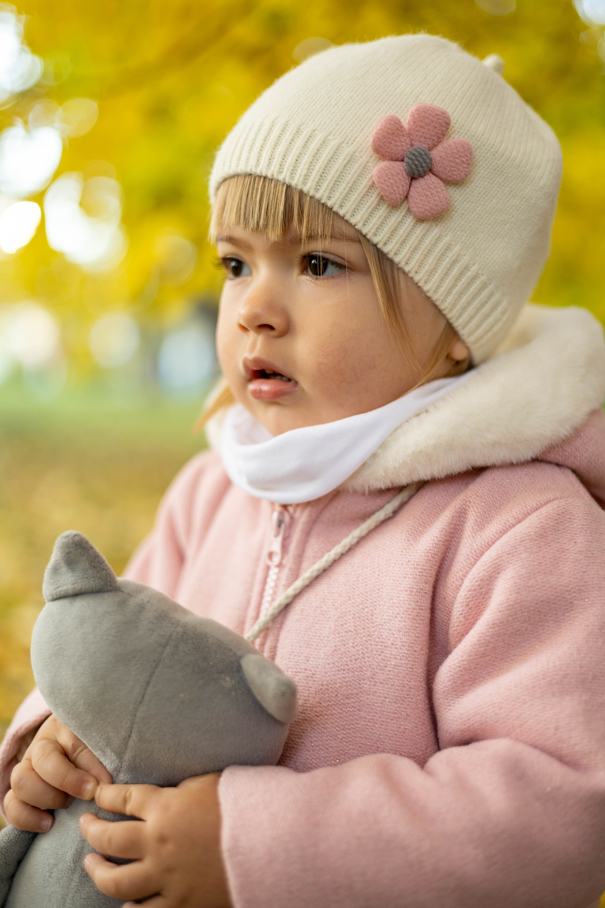 Девочка на фоне золотых деревьев с любимой игрушкой.