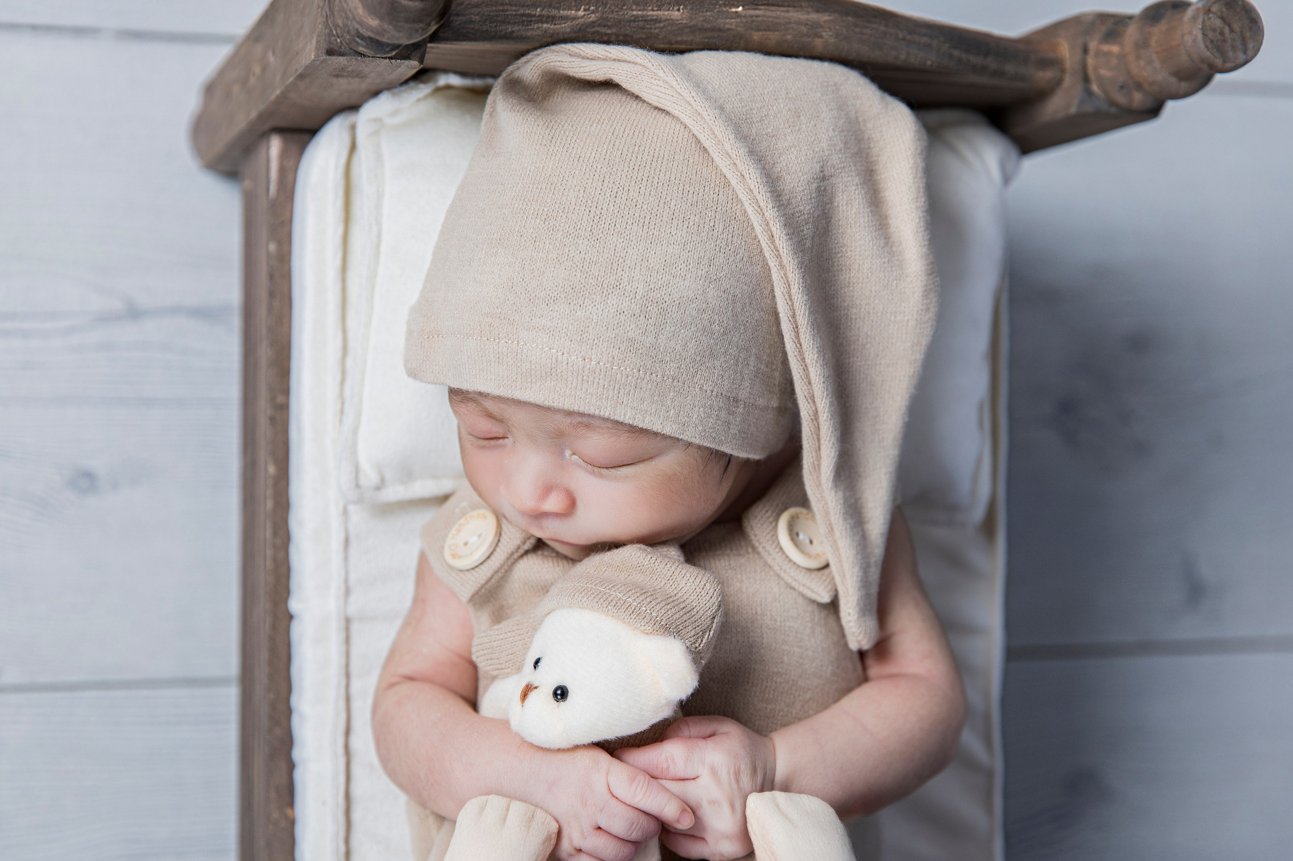 Fotografía de recién nacido dormido en posicionamiento seguro sobre posicionador beige, estudio newborn en Madrid.