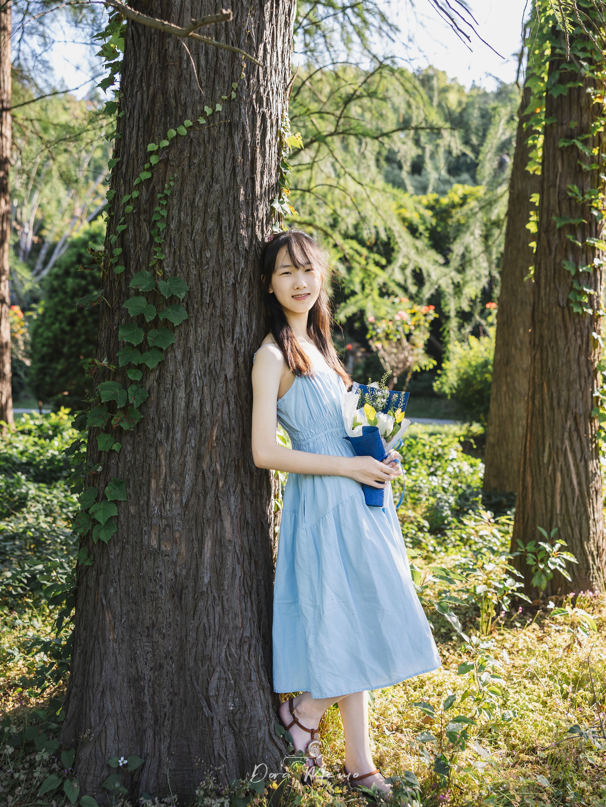Leaning against a tree, smiling softly | A 14-year-old leaning against a tree, smiling naturally in sunlight 
