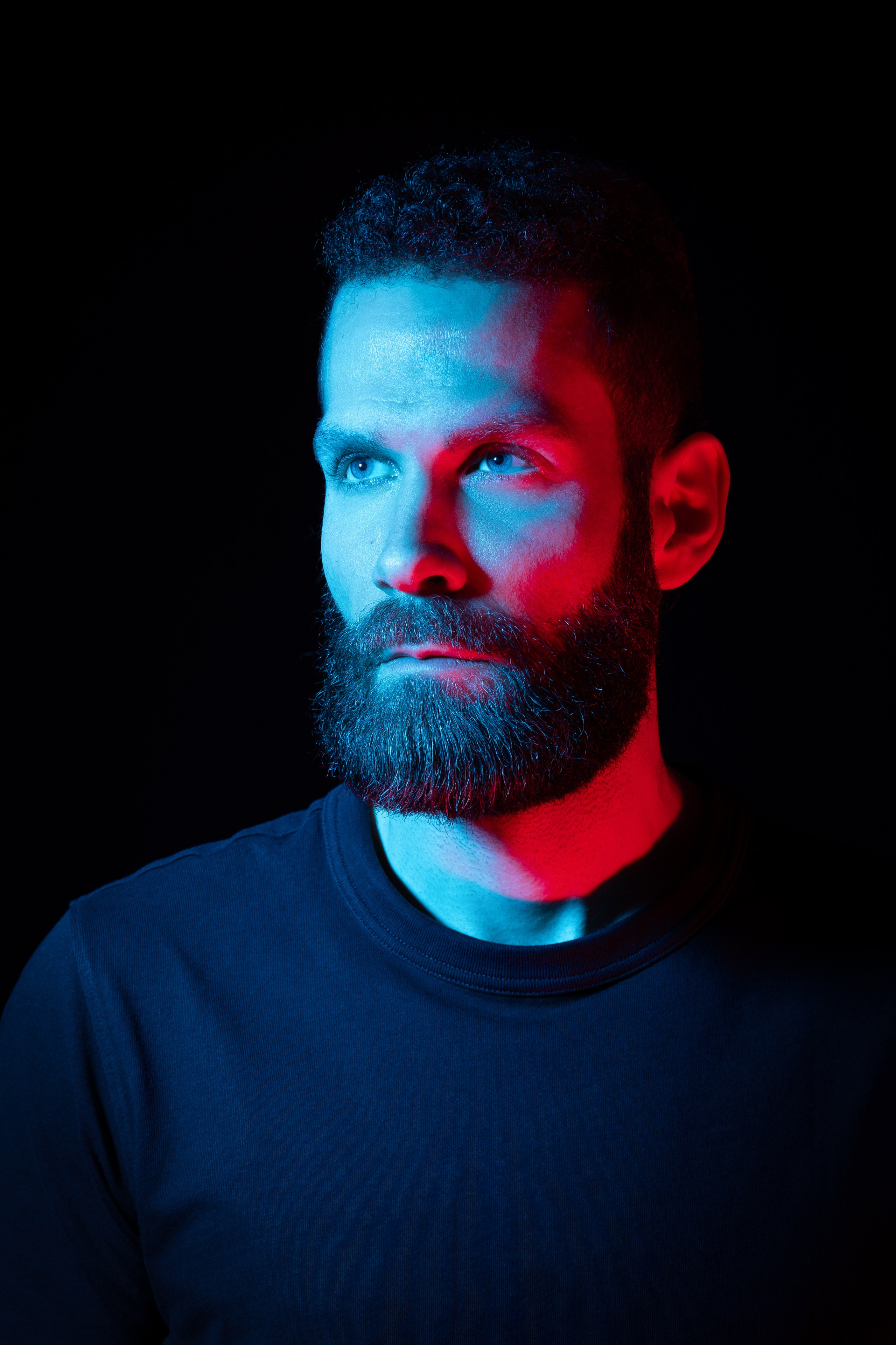 Brucktes Männerporträt mit farbigem Akzentlicht im dunklen Low Key
