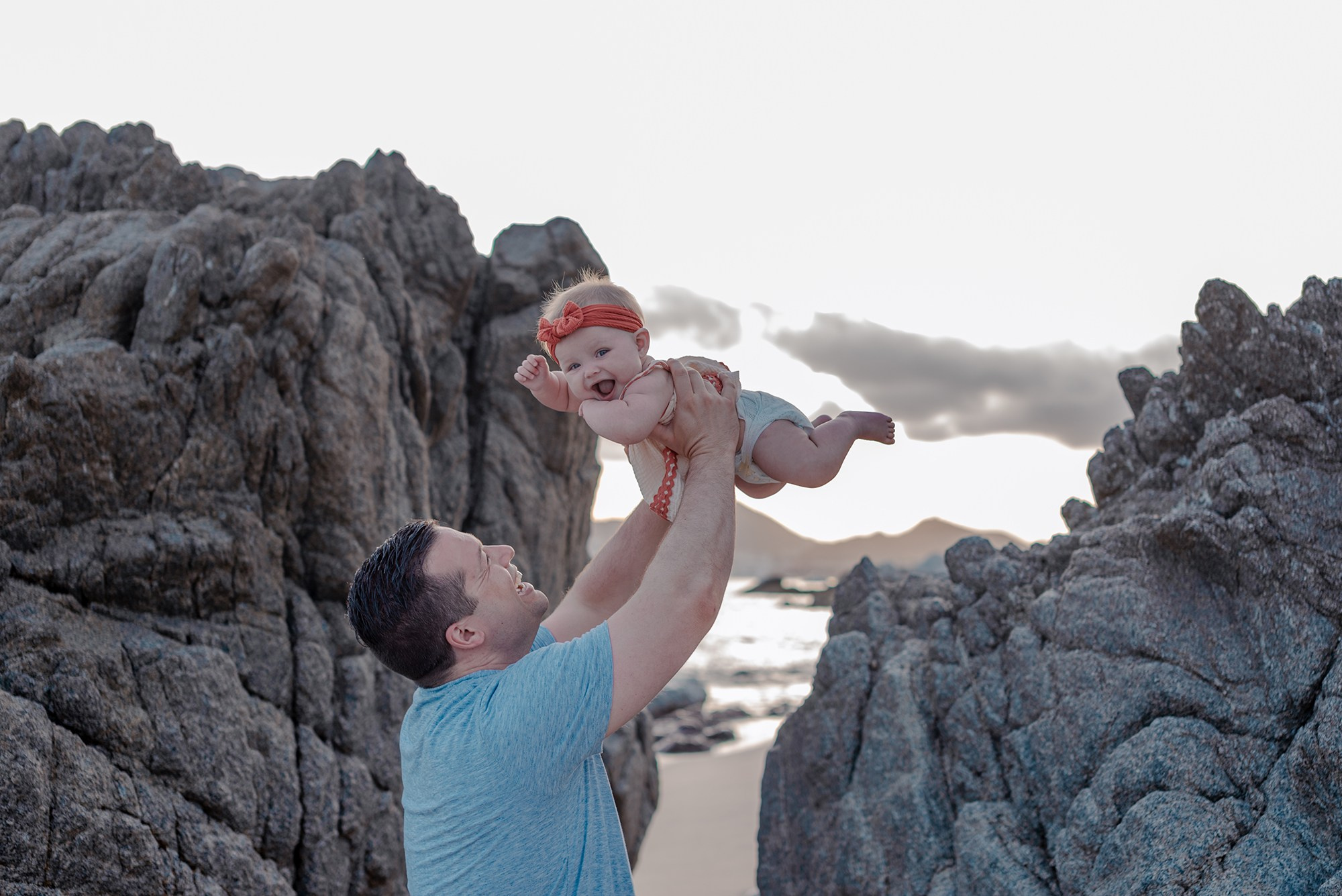 Family of four photographed at golden hour on Playa Monumentos with El Arco visible in the background Los Cabos