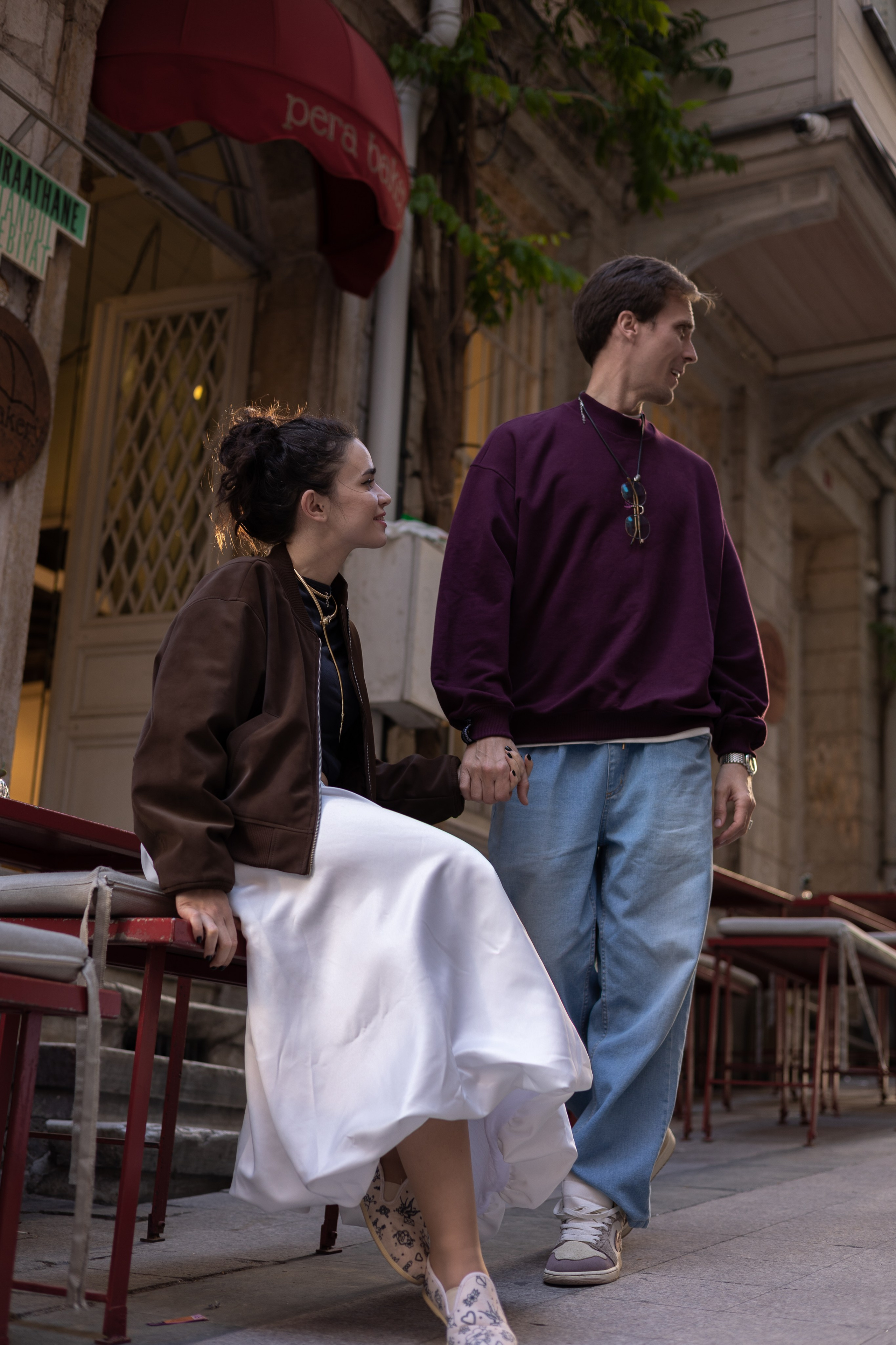 Пара держится за руки у столика уличного кафе на тихой улице района Пера в Стамбуле