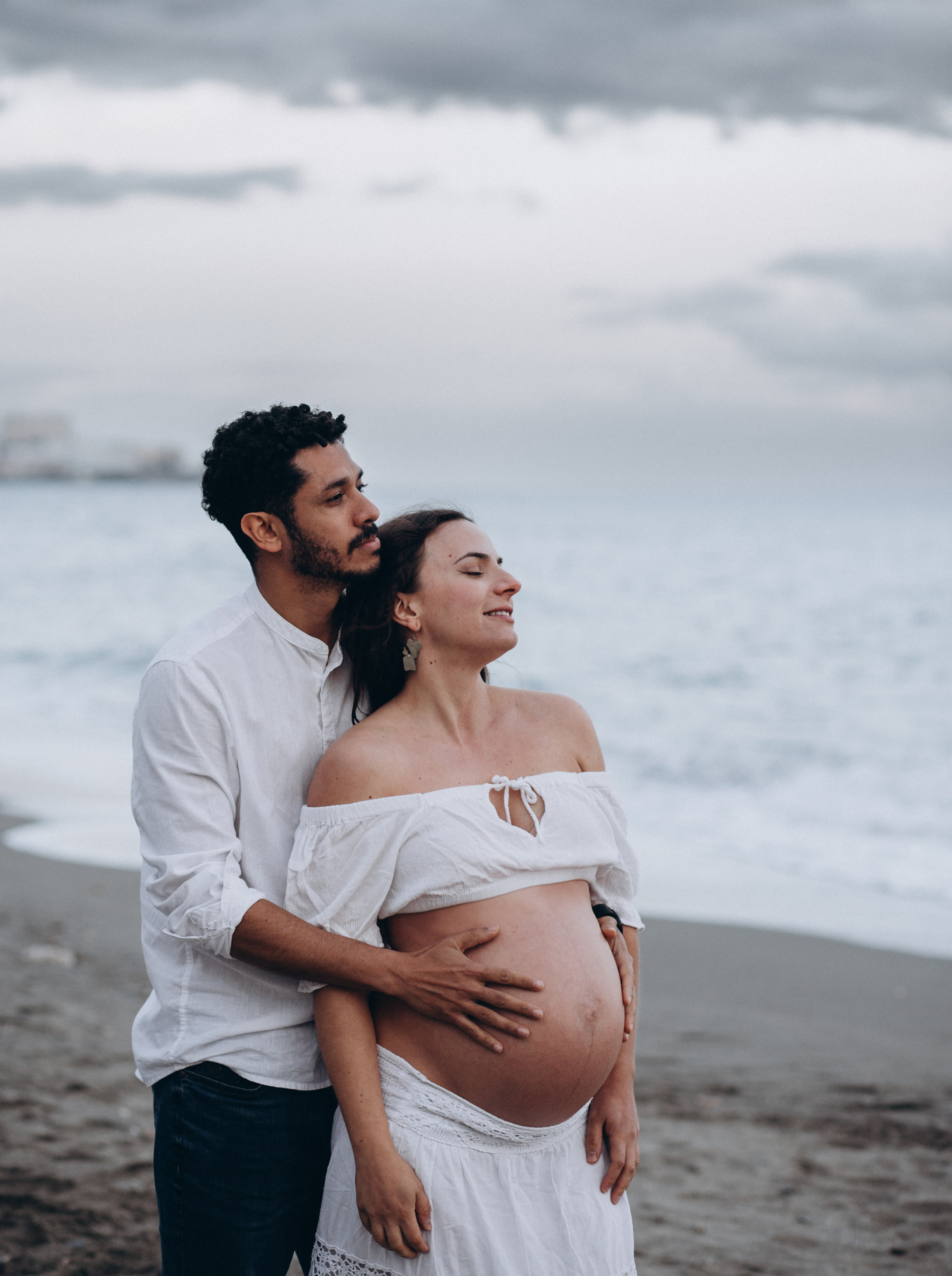 Sesión emotiva de embarazo en la playa de Barcelona, España — pareja abrazándose al atardecer, resaltando la belleza del embarazo, la conexión natural y el tranquilo litoral mediterráneo. Perfecta para quienes buscan sesiones íntimas y románticas de maternidad en Barcelona y la costa.