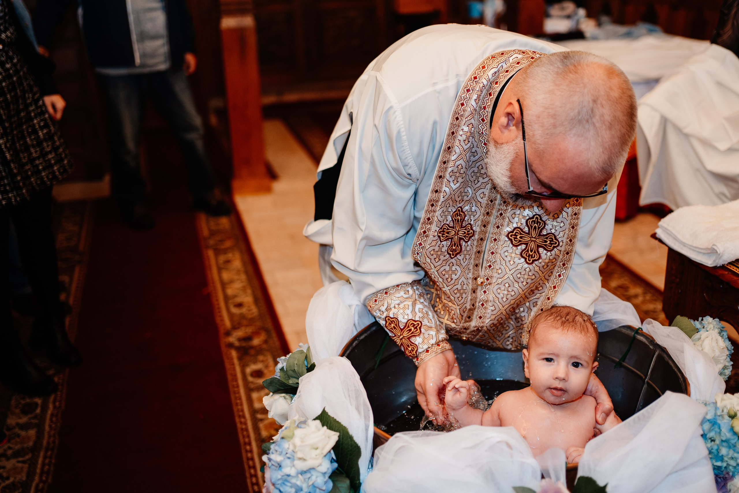 Instantaneu plin de tandrețe dintre părinți și bebeluș în ziua botezului, realizat în Bucuresti. Fotografie profesională de botez, capturând emoțiile autentice ale familiei într-un decor luminos și cald