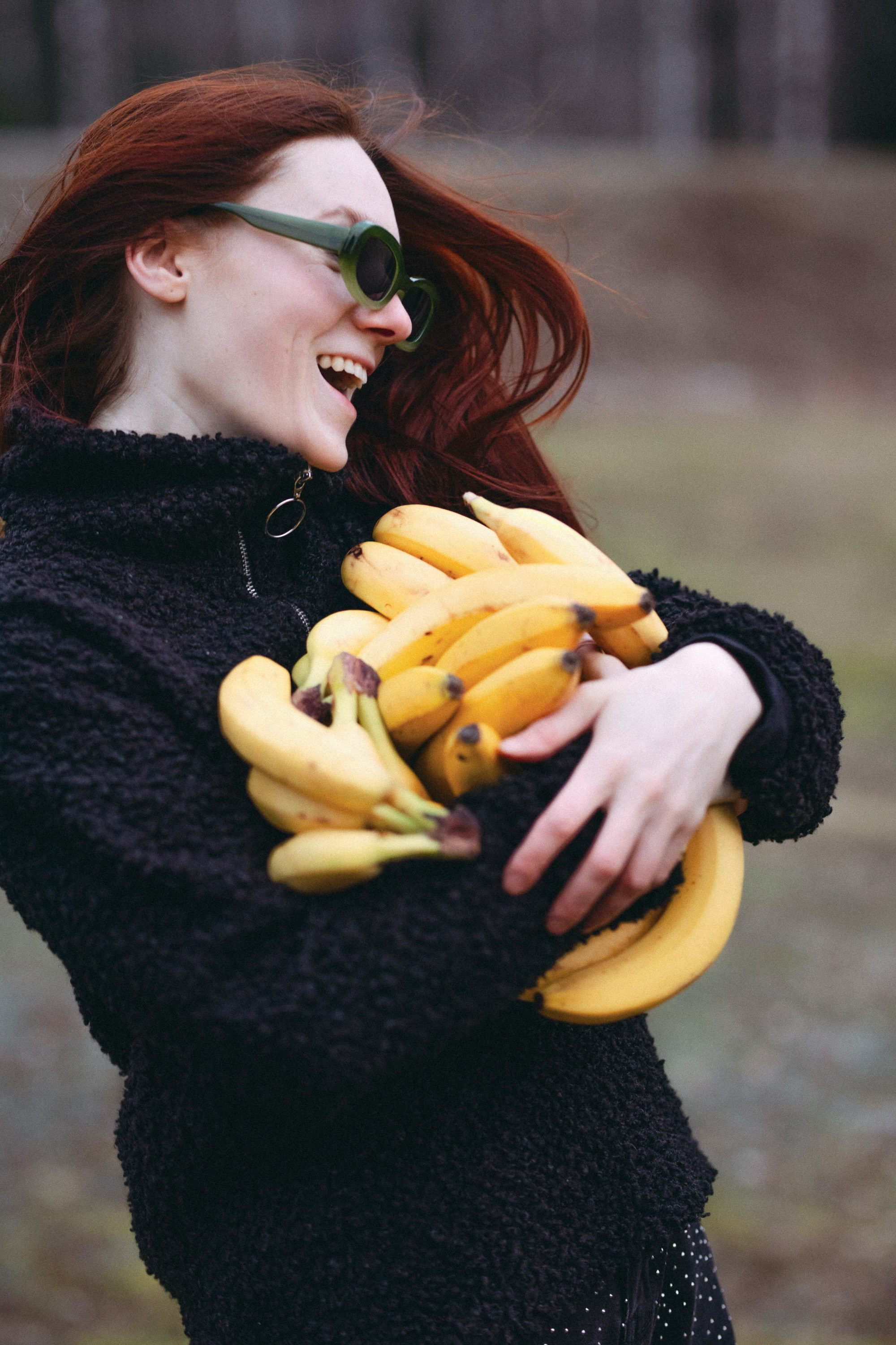 Hymyilevä tyttö pitää banaaneja sylissä, alkukevät