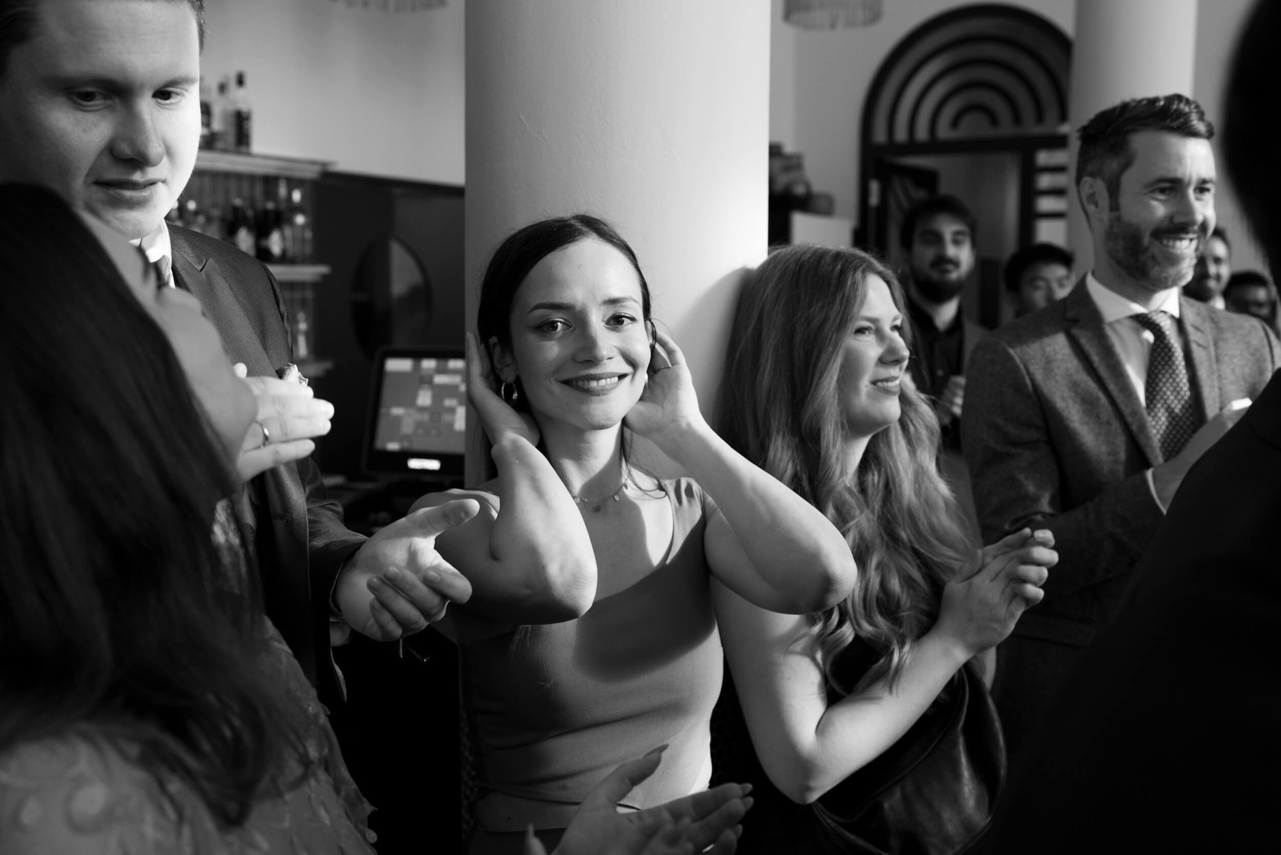 Black and white photo of wedding guests celebrating and laughing together at the reception, candid party moment at Bayerischer Hof Munich by Inna Zaytseva