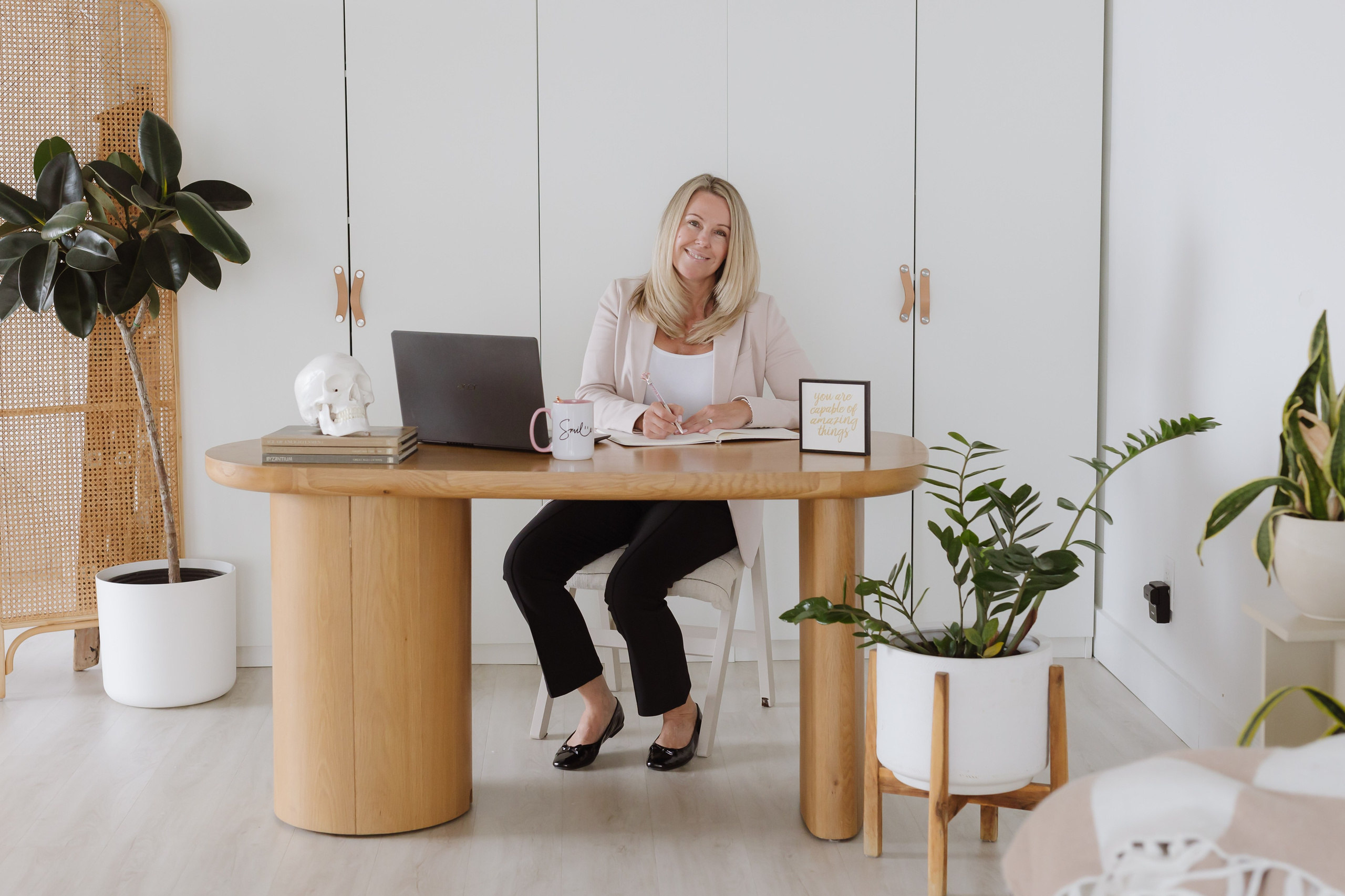 woman in pink blazer at desk working at computer 