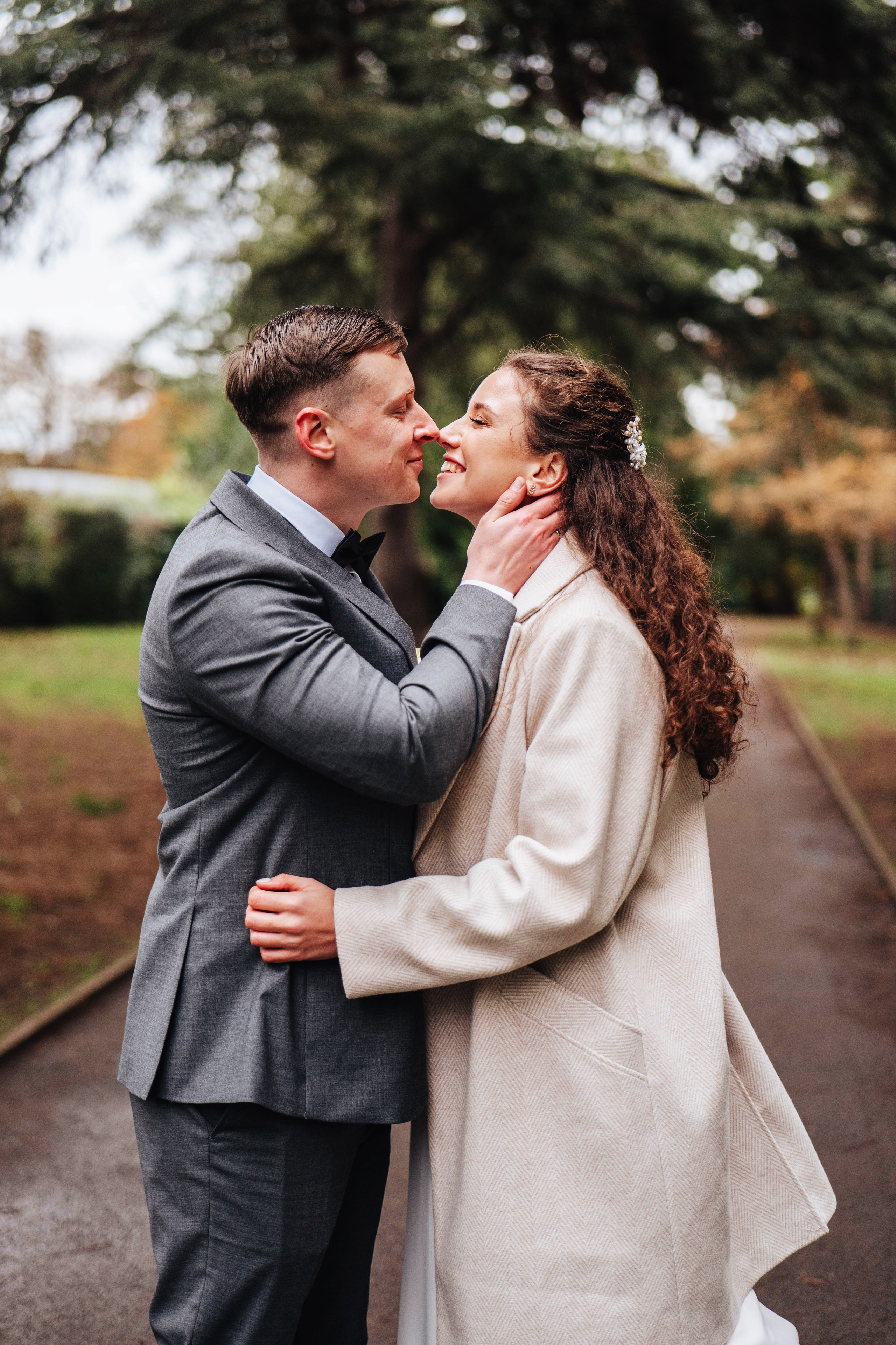 groom and bride kissing on path in the park