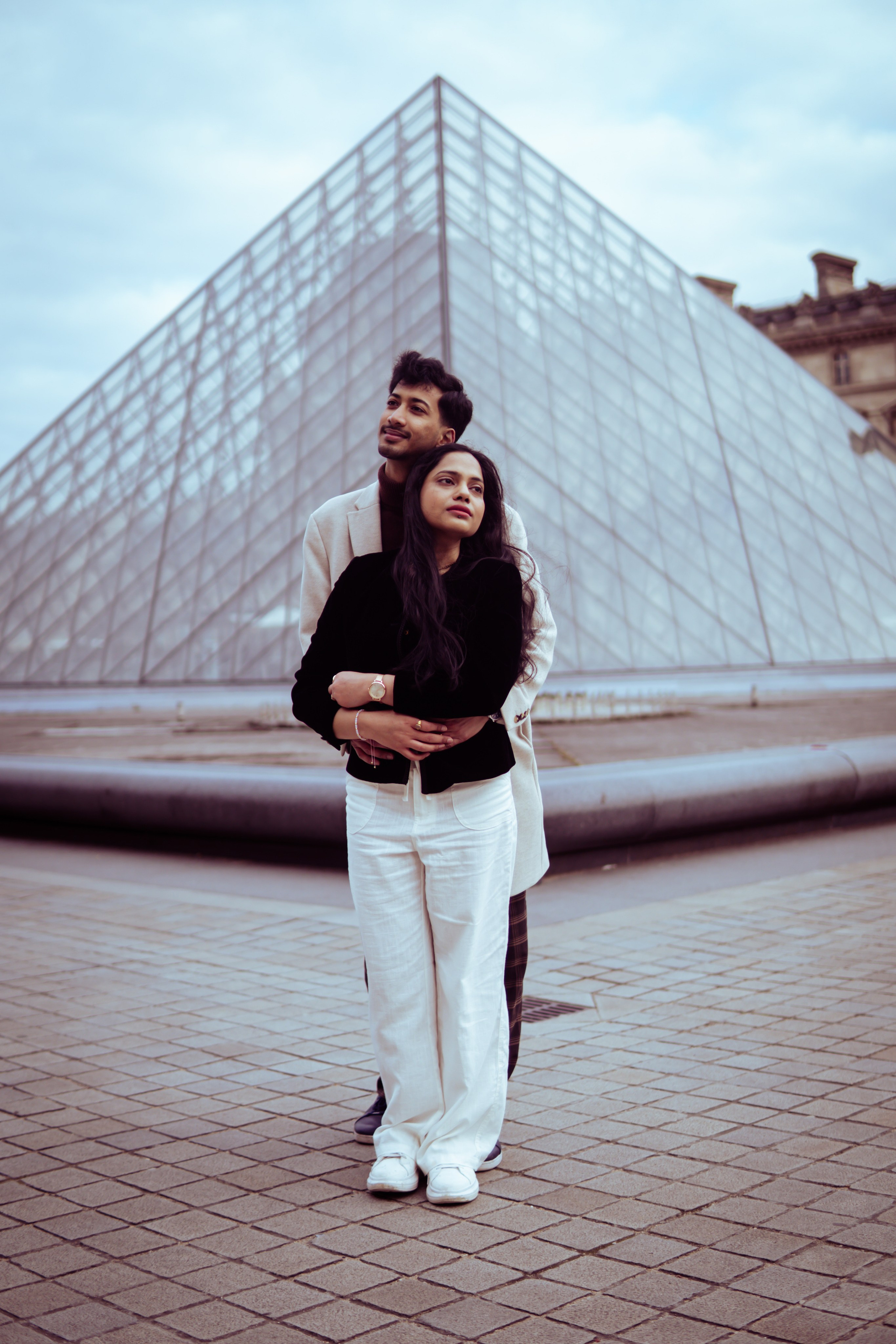 couple standing in front of louvre museum