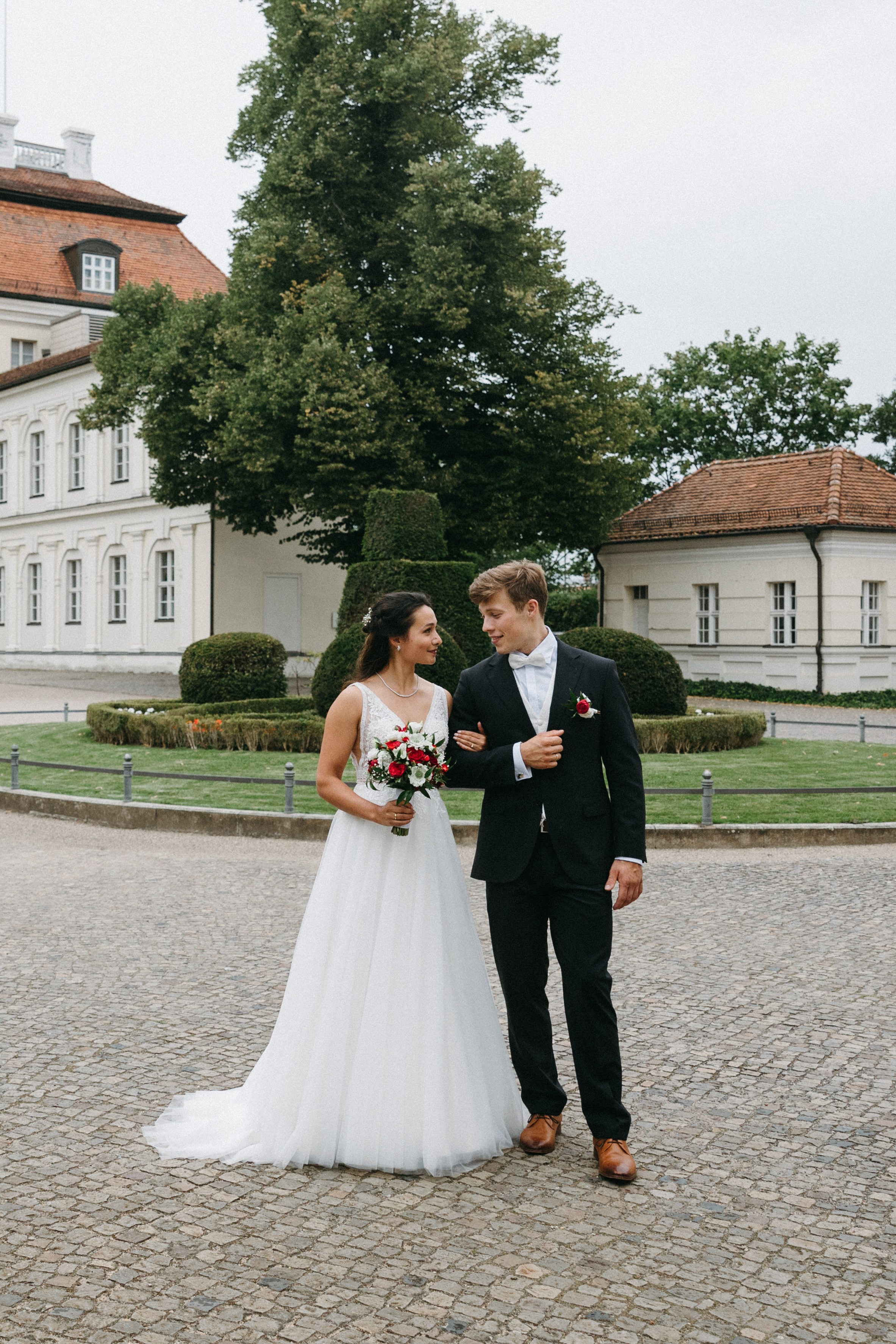 Frischvermählte gehen Arm in Arm im Hof des Schlosses Köpenick