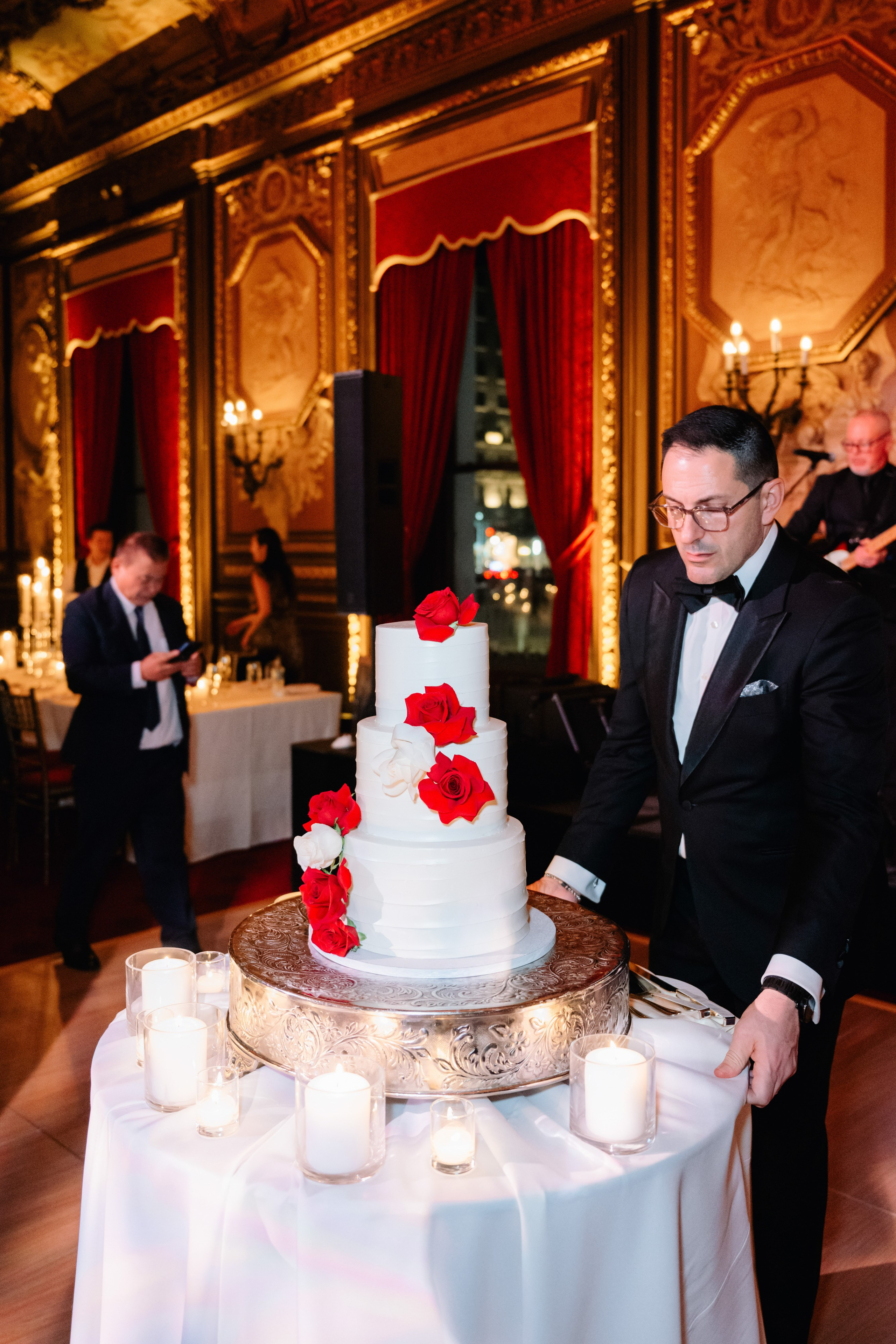 a man in a tuxed suit cutting a cake
