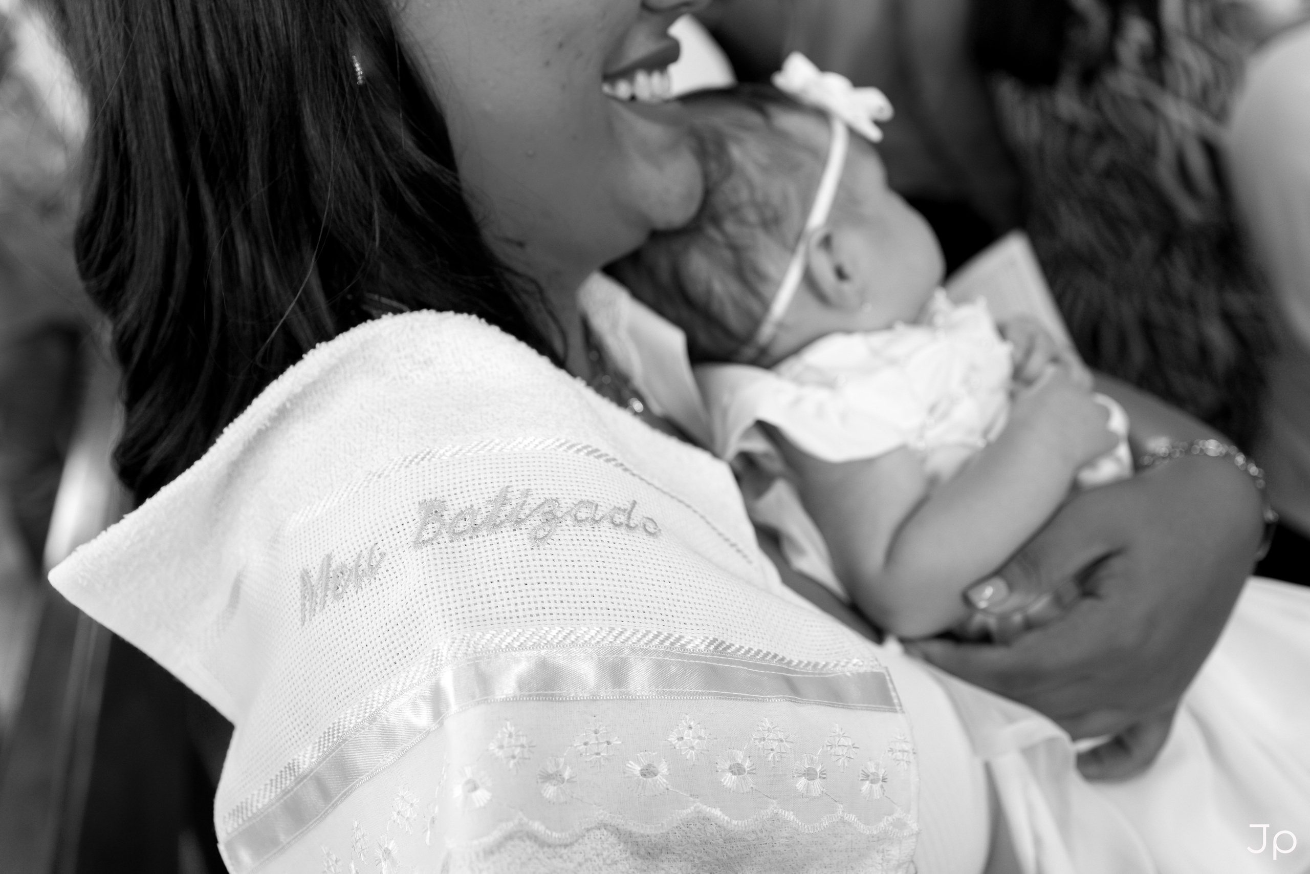 Bebê no colo da madrinha, usando roupa de batizado em Bariri