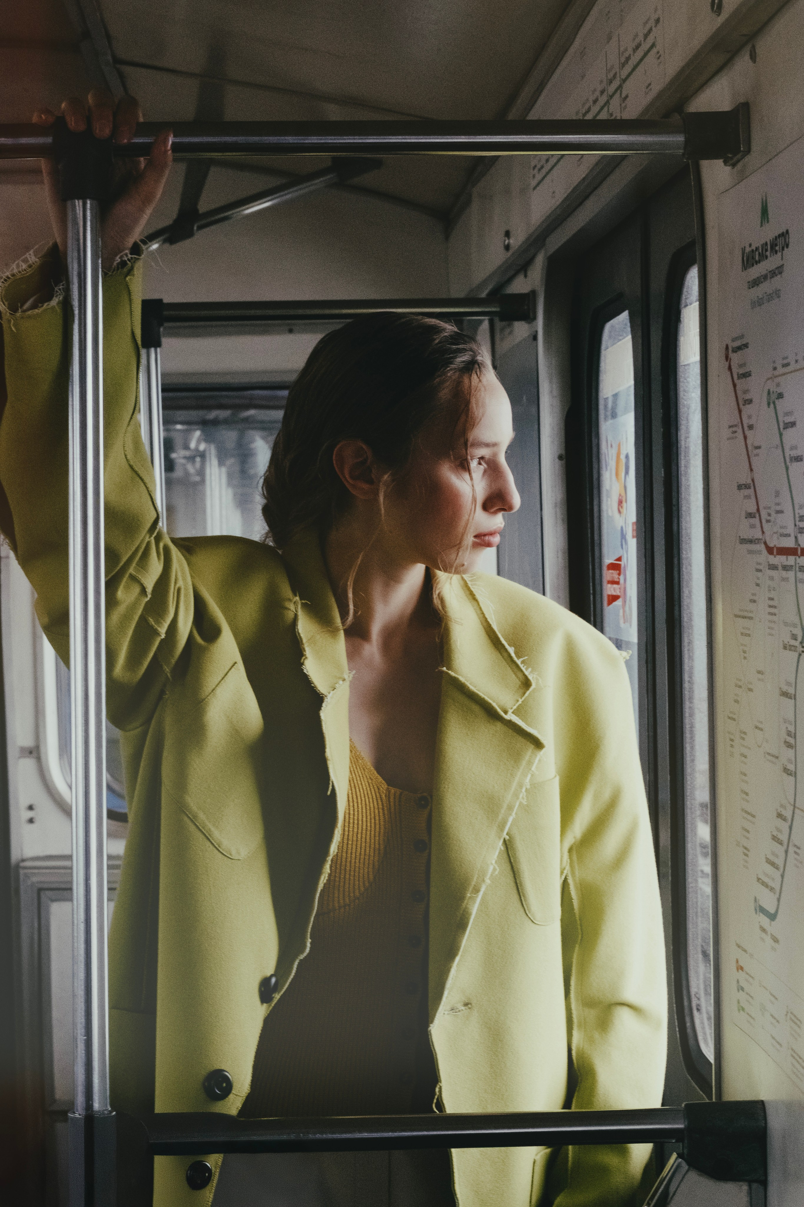 Dynamic street style campaign with a chartreuse yellow trench coat inside a train carriage. Urban Transit Series — Chartreuse Tailoring. 