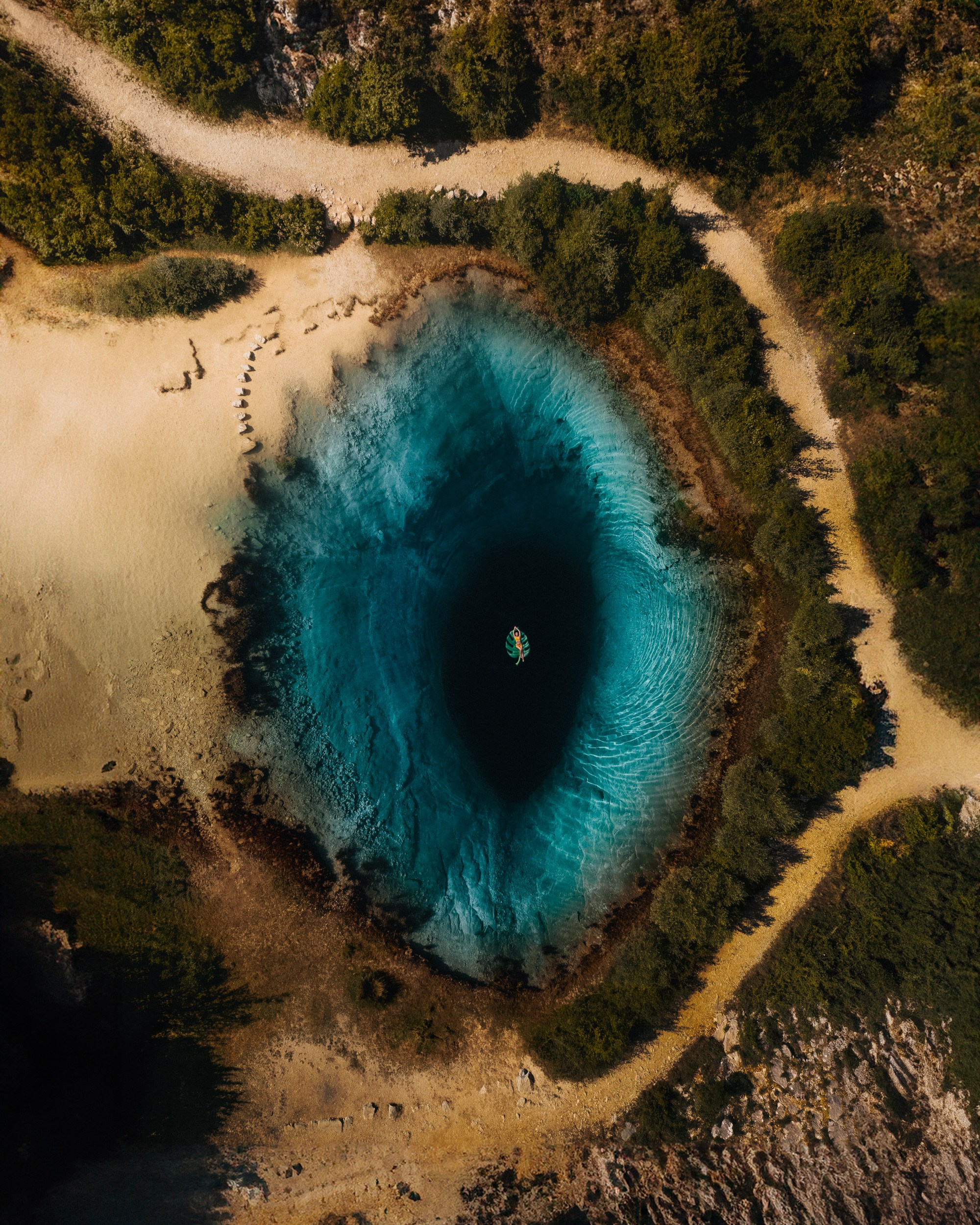 A drone photo of a woman floating in a lake in Croatia 
