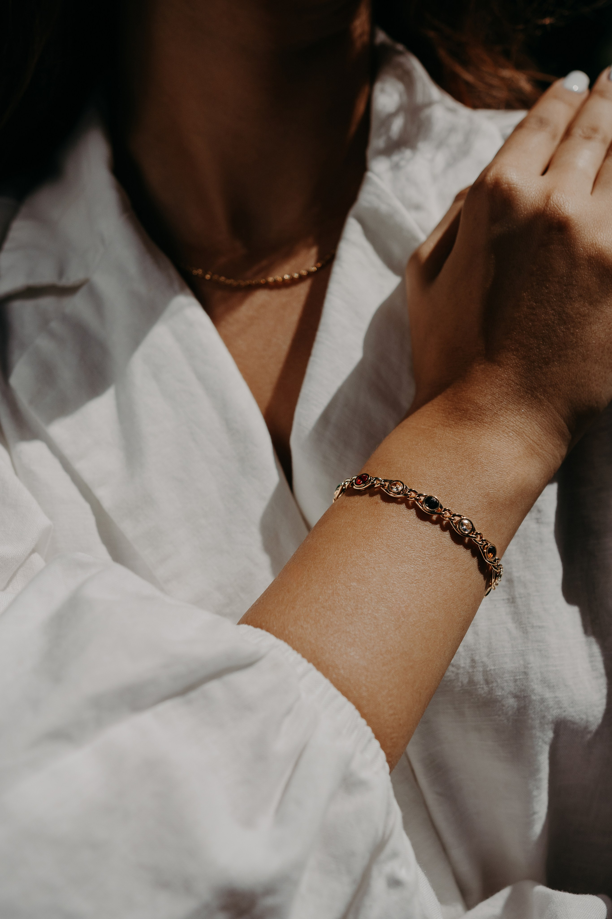 Close-up of a gold bracelet styled with a white shirt, representing timeless jewelry design.