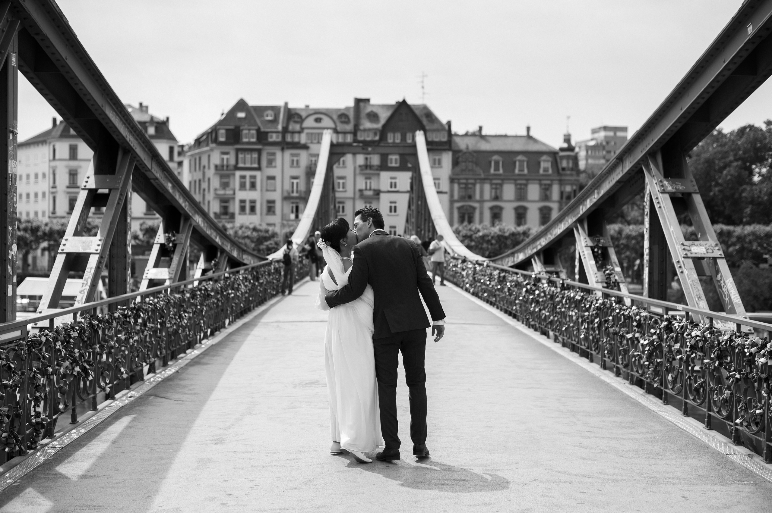 Brautpaar umarmt sich auf der Brücke über den Main in Frankfurt