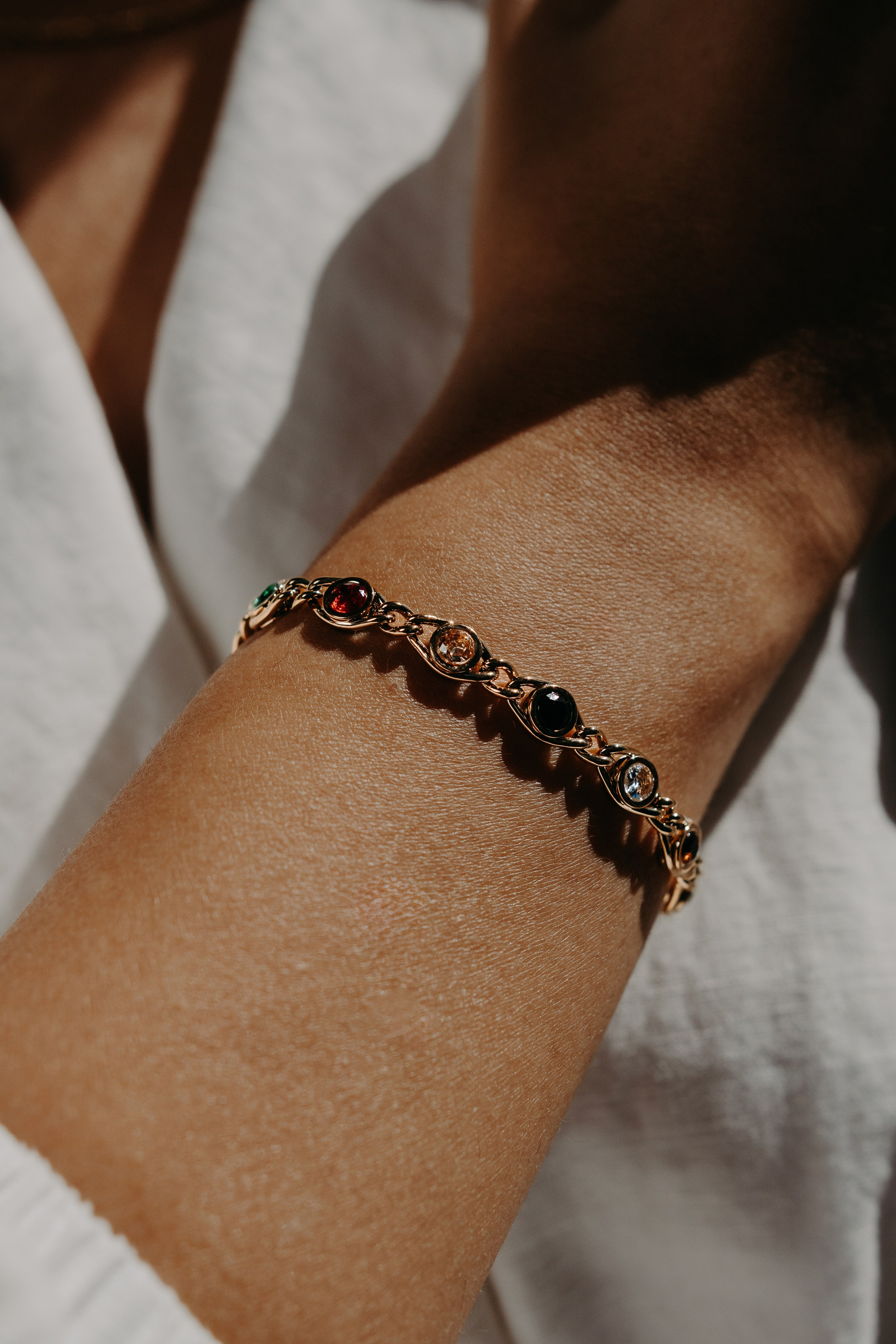 Tattooed model wearing a bold silver bracelet and layered necklaces, representing edgy fashion trends.