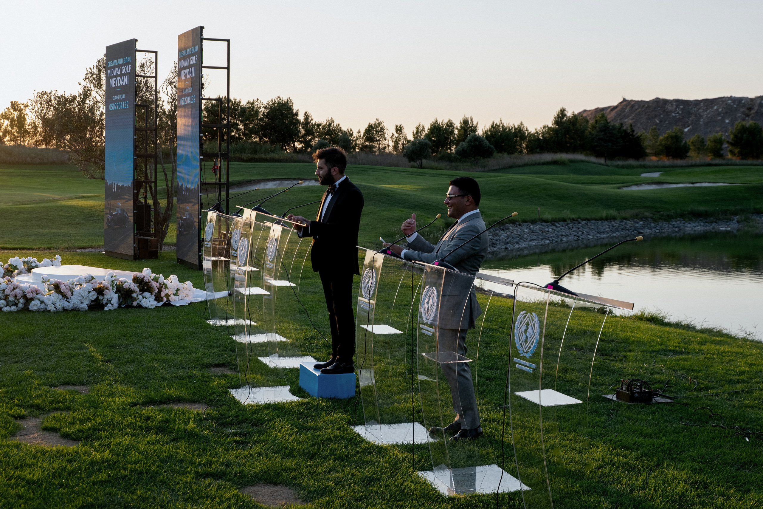 Transparent display panels bearing the Global HR and Leadership Forum 2026 branding on a sunlit lawn.