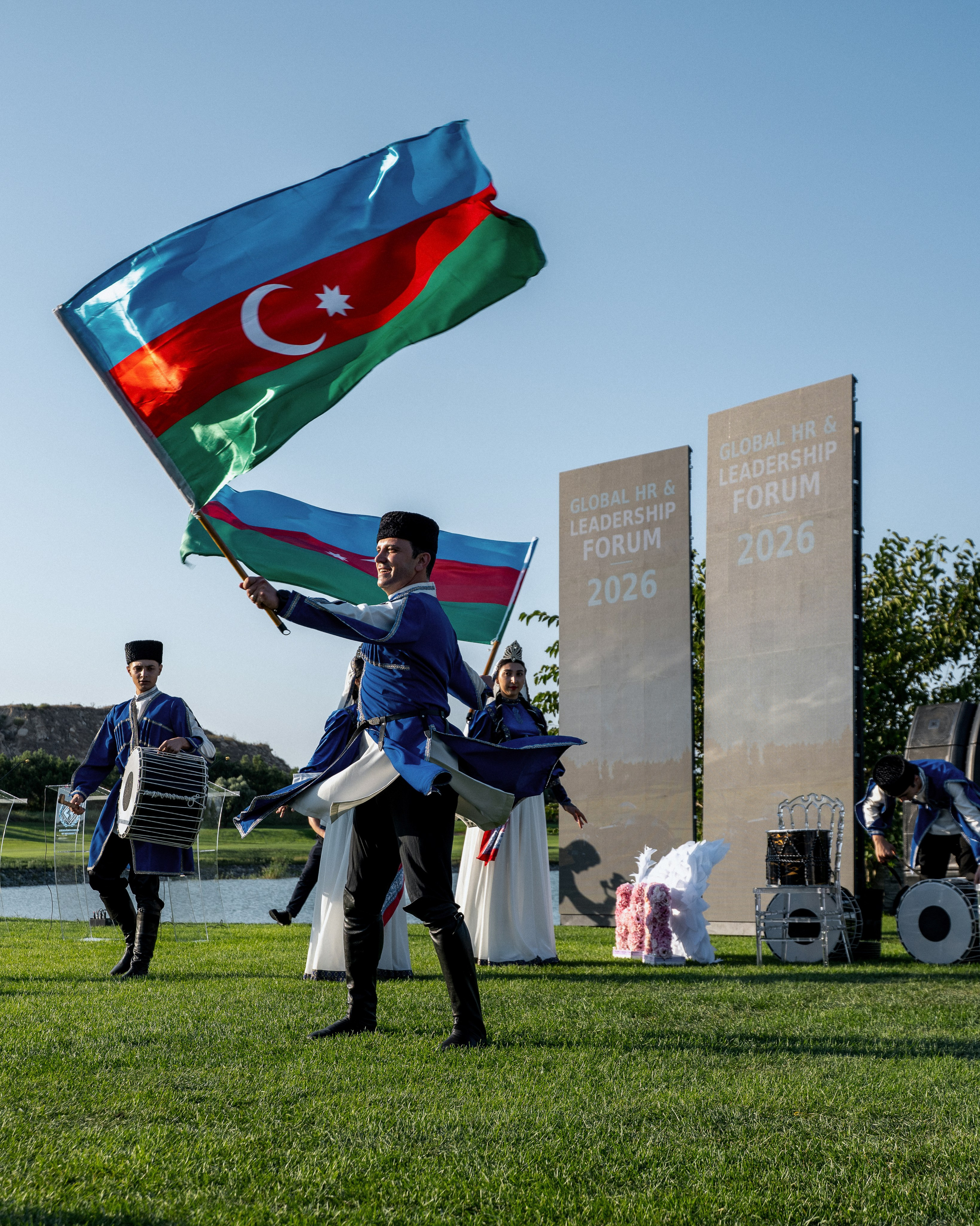 A performer carries the Azerbaijani flag during an outdoor performance in front of the forum audience