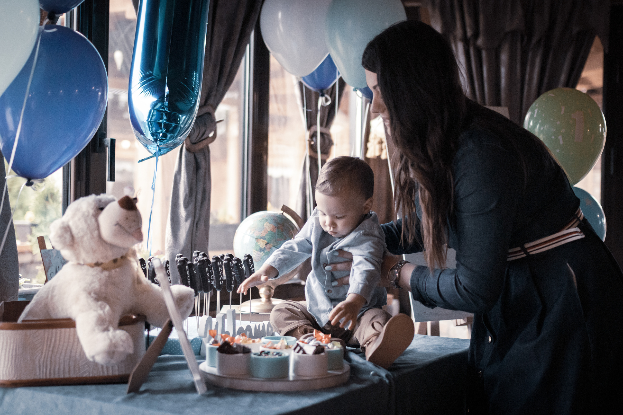 Fotografisanje malog dečaka na stolu sa majkom na proslavi prvog rođendana