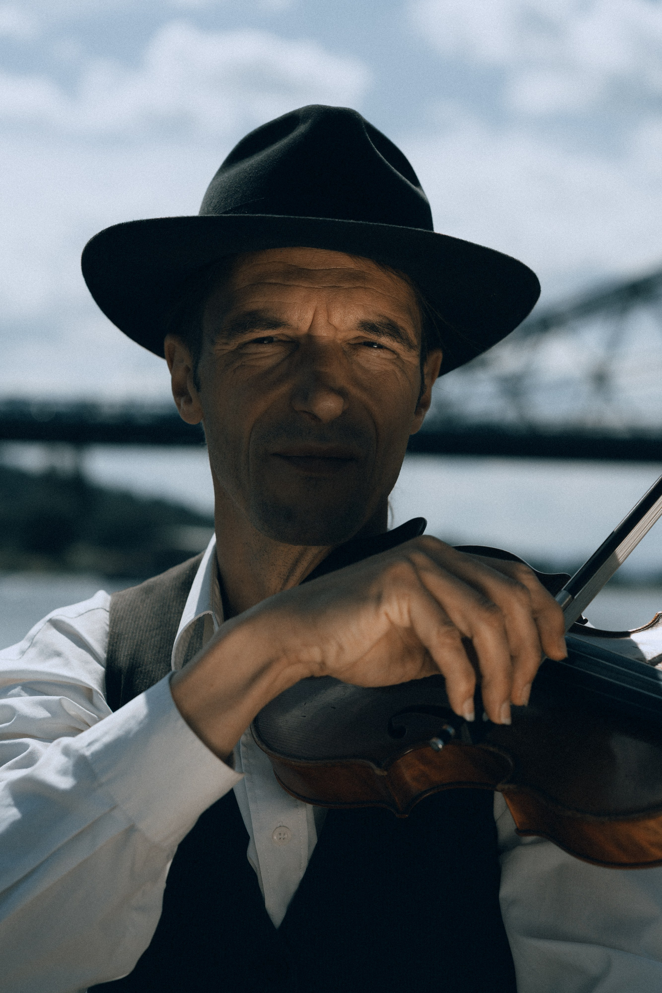 Violinist mit schwarzem Hut spielt Geige am Ufer der Elbe in Dresden