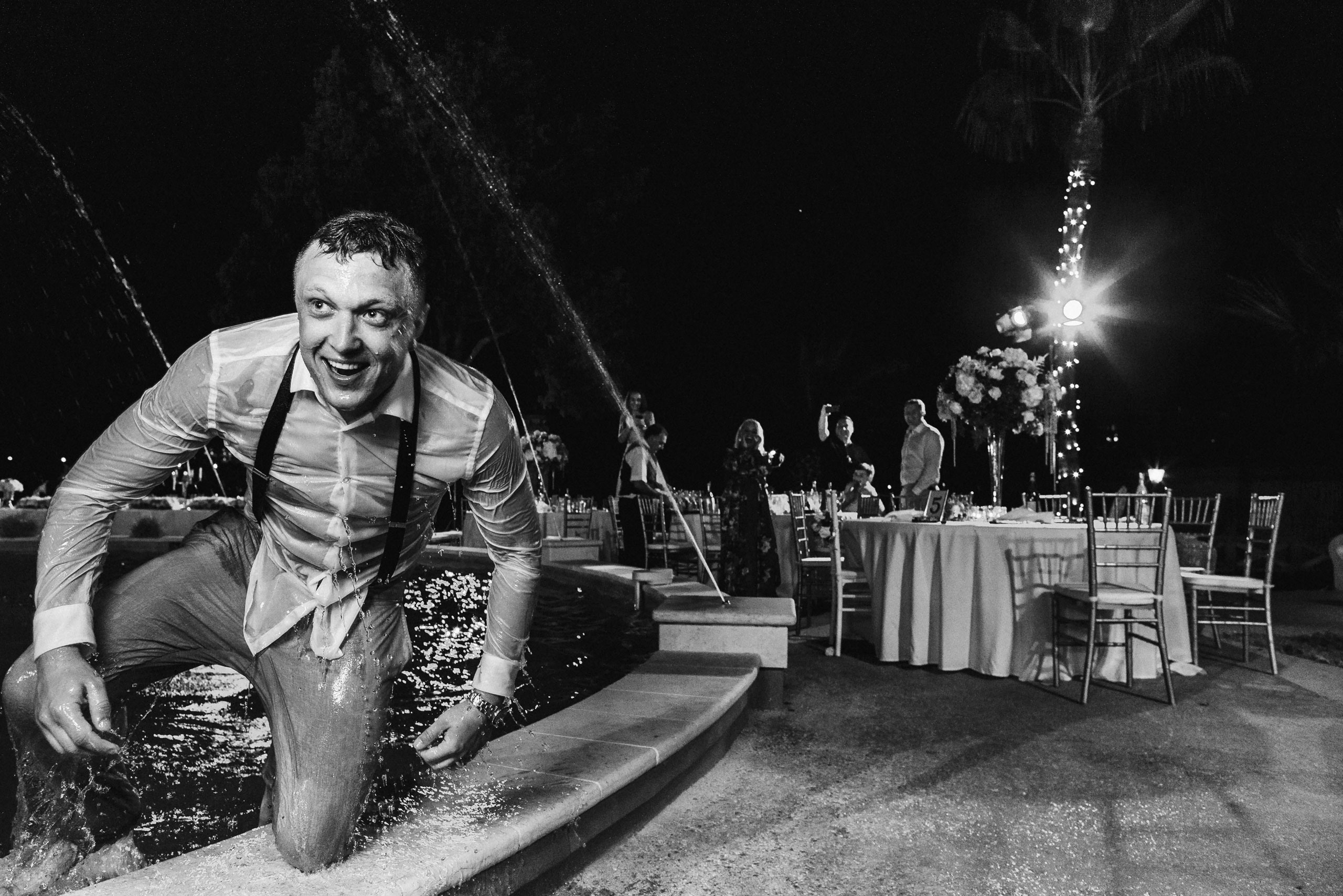 Человек в одежде и часах пытается выйти из бассейна